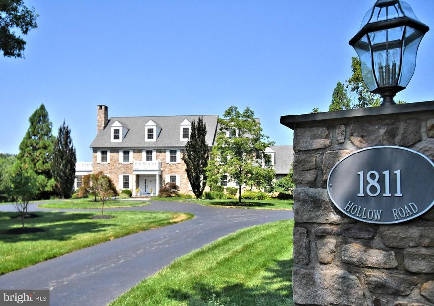 1811 Hollow Drive – Where Time Stands Still
There are homes that impress—and then there are homes that enchant. Built in 2009 by the master artisans of Zaveta, this nearly 10,000 sq. ft. estate feels as though it has stood for centuries, its presence as timeless as the stone from which it is built. Hand-selected, authentic stone elevations greet you at the end of a sweeping circular drive, framed by mature trees and lush plantings that whisper of a slower, more gracious time.
The grounds themselves are a living painting—bordered by protected township land, with a gentle stream winding alongside a  walking path. Here, mornings begin with birdsong and evenings end beside the glow of one of six fireplaces found throughout the property. In between, life unfolds around the resort-style pool with grotto, steaming hot tub, children’s splash pool, and charming pool house with its own bath. Flagstone terraces, an outdoor kitchen, and a pergola all create spaces meant for long, laughter-filled gatherings. For the collector or hobbyist, the estate offers both a two-car attached garage for everyday convenience and a separate detached two-car garage with attic space—ideal for storage, a workshop, or future studio.
Step inside, and the romance deepens. Every ceiling tells its own story—vaulted and crowned with trestles, delicately tray-framed, or lined in beadboard, just as they would have been in an 18th-century manor. The craftsmanship is unrivaled: rich custom millwork, solid wood doors crowned with transoms, deep-set window sills, and a foyer where an old-world arch frames a sweeping staircase with a view straight through to the gardens beyond.
The formal dining room, able to host twenty with ease, is served by a butler’s pantry complete with a catering kitchen. The main gourmet kitchen is a culinary sanctuary—two Sub-Zero refrigerators, dual convection ovens, a grand granite island, and ceilings that soar eighteen feet overhead. The living spaces flow like poetry: a formal living room with fireplace and custom built-ins; a four-season stone hearth room with fireplace, reminiscent of an enclosed porch from another era; a cherry-paneled library for quiet study; and a family room with solid wood trestles and a towering stone fireplace that seems to warm both the body and the soul. Additional fireplaces grace the primary suite, the lower level, and the outdoor living area, making warmth and ambiance a constant companion.
Upstairs, five bedrooms each offer their own walk-in closets and private retreats. The primary suite is a sanctuary unto itself, with vaulted trestled ceilings, a balcony worthy of a film scene, and a bath dressed in Calcutta marble—an oversized herringbone shower, soaking tub, dual vanities, and a private water closet.
The enchantment continues on the walkout lower level, where leisure and indulgence meet. A stone-accented wine cellar awaits your finest vintages, while a custom wood bar invites evenings of laughter and conversation. There’s a game room for spirited competition, a dedicated craft room for creative pursuits, and a guest bedroom with its own private bath. An additional powder room, abundant storage, and direct access to the outdoors make this level as functional as it is inviting. 
From its three-story elevator to the unfinished walk-up attic and  state of the art utilities this well thought out masterpiece is awaiting its next chapter, this is a home built for a lifetime, yet crafted to feel like it has already lived one.
At 1811 Hollow Drive, you don’t just purchase a property—you inherit a legacy.