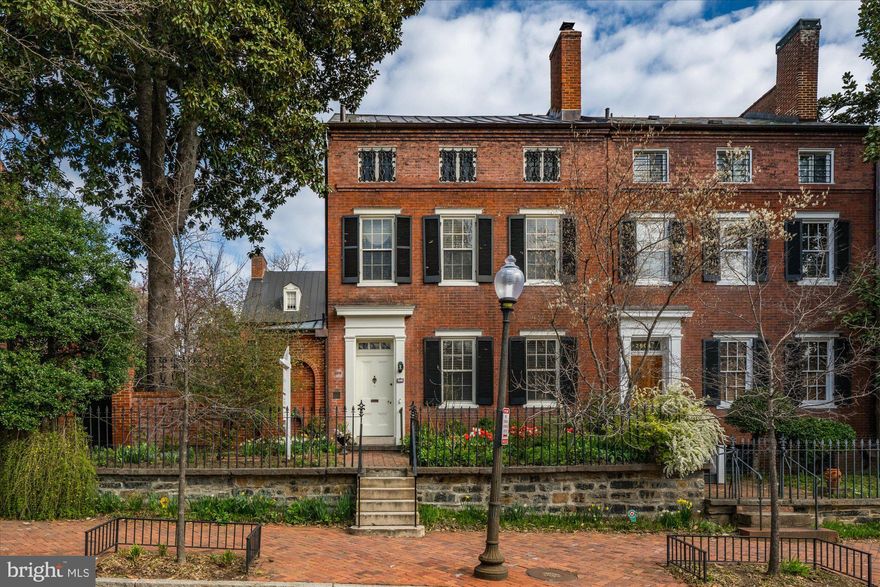 Welcome to a truly remarkable piece of Georgetown’s rich history, nestled in the prestigious East Village. This gracious notable residence, which is protected by a historic easement, was designed by Reuben Daw and constructed circa 1843, stands as a testament to timeless elegance and sophistication. Once
the home of Dean Acheson, United States Secretary of State, this exquisite property offers an unparalleled blend of historic charm and elegance. The front facade to 2805 is enhanced by the original wrought iron fence, crafted from gun barrels from the War of 1812. Few properties in Georgetown can boast of this unique architectural feature.

Spanning an impressive 6,350 square feet, the home houses seven spacious bedrooms and seven and a half bathrooms. The grand interiors are flooded with natural light, featuring large rooms
perfect for entertaining or quiet reflection.

Upon entering, the Entry Hall guides your view to the Loggia with its elegant arches leading to expansive rooms. The study, complete with a wood-burning fireplace and built-in shelves, comfortably accommodates couches and chairs, creating an inviting retreat. The grand dining room, illuminated by a crystal chandelier, is perfect for hosting cozy intimate gatherings or large formal dinners. The formal living room is a magnificent space, featuring multiple seating options and a grand piano, ideal for musical gatherings. Its wood-burning fireplace and built-in shelves add to the room’s charm.

So come and enjoy the tranquil ambiance of the elegant side patio and garden, accessible through French doors from the loggia. The patio is a wonderful venue that has hosted festive weddings, family gatherings, and countless formal and informal parties/events. The rear garden features a refreshing lap pool, while the property also includes a convenient PARKING PAD FOR TWO VEHICLES. Culinary enthusiasts will appreciate the eat-in kitchen and butler’s pantry, while wine connoisseurs will delight in the two
temperature-controlled wine cellars, each accommodating around 1500 bottles. With six working fireplaces enhancing its charm, this residence is a rare opportunity to own one of Georgetown’s most storied and beautiful homes. Experience the perfect blend of history and luxury in this magnificent property.