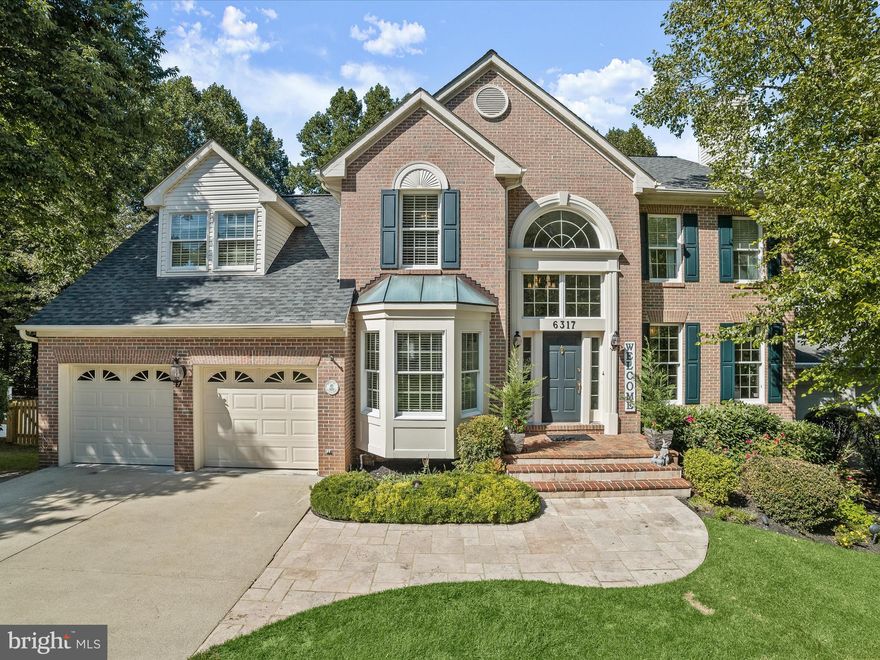 Tucked away on a quiet cul-de-sac in the coveted Village of River Hill is a private oasis with exceptional designer upgrades inside and out. Inside, light streams in from an arched clerestory window over the entry door and announces arrival into a grand two-story foyer with gleaming hardwood floors, strong crown, and window box moldings.  
Beautiful hardwoods and upgraded door hardware continue throughout the main level as the foyer unfolds into a light-filled formal living room that is host to four windows, a gas fireplace, and beamed ceilings. The floor plan opens to a formal dining room with a center window  framed by built-in cabinets, and there is a secondary entry into the upgraded cook’s kitchen.  A pantry closet, stainless appliances, designer subway tile back splash, and sleek white cabinetry wrap the center contrast center island while the breakfast bar transitions into the adjacent breakfast room.  The atrium door invites guests  out to elegant outdoor living and dining on a low-maintenance, composite deck with a low maintenance vinyl clad and clear-view rail system. Guests can  easily meander in and out as they gather in the open plan kitchen, breakfast room and family room. Living, dining, and entertaining is easy and seamless with this circular floor plan by Douglas Builders. A dramatic wall of windows with arched transoms,  carpet, and a vaulted ceiling defines the spacious family room, and a commanding gas fireplace embellished with floor to ceiling stone takes center stage.  The main level floor plan circles back through French doors to the foyer where the powder bath, study and open, winding stair with a carpet runner complete the main level.
Upstairs, French doors open into the luxurious primary bedroom suite that is upgraded with designer elegance at every turn.  Prepare to fall in love with the fully upgraded, resort-styled bath that is equipped and finished with every luxury amenity. Decompress in a free-standing soaking tub situated under a window with up/down shades and a hand-held spray feature, or, enjoy a walk-n shower customized with rain shower, body sprays, and hand-held sprayer. Opposite the frameless glass shower is a built-in designer linen tower and cabinet that is articulated with mirror and fret details that highlight and sparkle.  The same level of exquisite design and detail continues onto every wall with painted board and batten as a unifying element.  A seated make-up station is sided by two separate vanities with stone tops, customized mirrors, and elegant sconces that are impeccably integrated into the board and batten detail with high style.  The primary suite offers an expansive, walk-in dressing closet outfitted with a wardrobe organizer system that includes four bays of drawers, two shoe towers, cubbies, and hanging enough for two complete wardrobes! Start and end your days bathed in the private luxury offered in this primary bedroom suite with up-to-the-minute details and finishes you will love!  The upper-level landing overlooks the foyer and separates the private primary wing from three additional bedrooms with individual designer feature walls and a hall bath.
Downstairs, a thoughtful design offers lifestyle  flexibility for In-laws, Au-pair, or guests.  A fifth bedroom and fully upgraded full bath are adjacent to a very large and open recreation room, breakfast room, and kitchenette complete with cabinetry, stainless sink, and full-size fridge.  The lower level offers two full-sized daylight windows and a walk-out slider to a paver patio and hot tub. Relax outside in your own resort-styled paradise on the tiered deck and tree-fringed lawn. Lush professional landscaping, lighting, and seasonal blooms, are maintained effortlessly with underground irrigation, and a drip system for potted plants and flowers.  Come home and enjoy luxury living, lifestyle options, and exquisitely upgraded designer elegance in this beautiful residence located in River Hill!