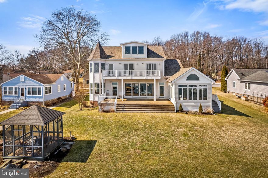 Set on a rare 100-foot-wide raised double waterfront lot (NO FLOOD INSURANCE REQUIRED!) this extraordinary six-bedroom, five-and-a-half-bath home captures breathtaking, unobstructed eastern views over the Middle River looking out at Pooles Island and toward the Eastern Shore and the Chesapeake Bay. From sunrise reflections on the water to expansive panoramic vistas from every level, this property offers a truly one-of-a-kind waterfront experience — all just 30–40 minutes from downtown Baltimore.
Designed for both everyday living and effortless entertaining, the main level features an open-concept floor plan anchored by a spacious chef’s kitchen with an oversized island — perfect for gatherings. The kitchen flows seamlessly into the family room, dining area, and a separate sunroom, all lined with oversized Andersen windows and doors that flood the home with natural light and frame stunning water views. Step outside onto the expansive deck for outdoor dining, sunset cocktails, or simply taking in the peaceful waterfront setting.
The main level also includes a home office, laundry room, powder room, and a sun-filled primary ensuite with direct deck access — ideal for morning coffee overlooking the view.
Upstairs, you’ll find five bedrooms, many with oversized windows and glass doors leading to balconies that continue the home’s spectacular water views. A third-floor bonus room offers flexible space for a playroom, studio, or additional guest quarters. The finished lower level features a family room, full bath, and an additional flex room ready to suit your needs.
Built for hosting, the property provides exceptional parking and guest accommodations, including:
Attached two-car garage, driveway parking for six vehicles, detached two-car garage with its own main-level foyer and full bath with a finished second-floor bonus room above the detached garage — perfect for guests, a gym, office, or entertainment space.
Outdoor living is where this home truly shines. The private pier has been re-decked and includes both a boat lift and jet ski lifts, making boating, fishing, crabbing, paddle boarding, kayaking, and jet skiing part of your everyday lifestyle. With direct access to the Middle River and quick access to the Chesapeake Bay, this is waterfront living at its finest.
Meticulously maintained and thoughtfully upgraded, improvements include: Geothermal energy system, New roof (2017), New Andersen doors, Re-decked pier, Multiple hot water heaters, Energy-efficient appliances, including a Sub-Zero refrigerator, New driveway, Whole-house vacuum system, Two owner-owned 500-gallon propane tanks servicing hot water heaters, dryer, stove, and a backup Generac generator.
Offering space, views, functionality, and an unparalleled waterfront lifestyle — this is a rare opportunity to own a premier Middle River property combining privacy, luxury, and convenience.