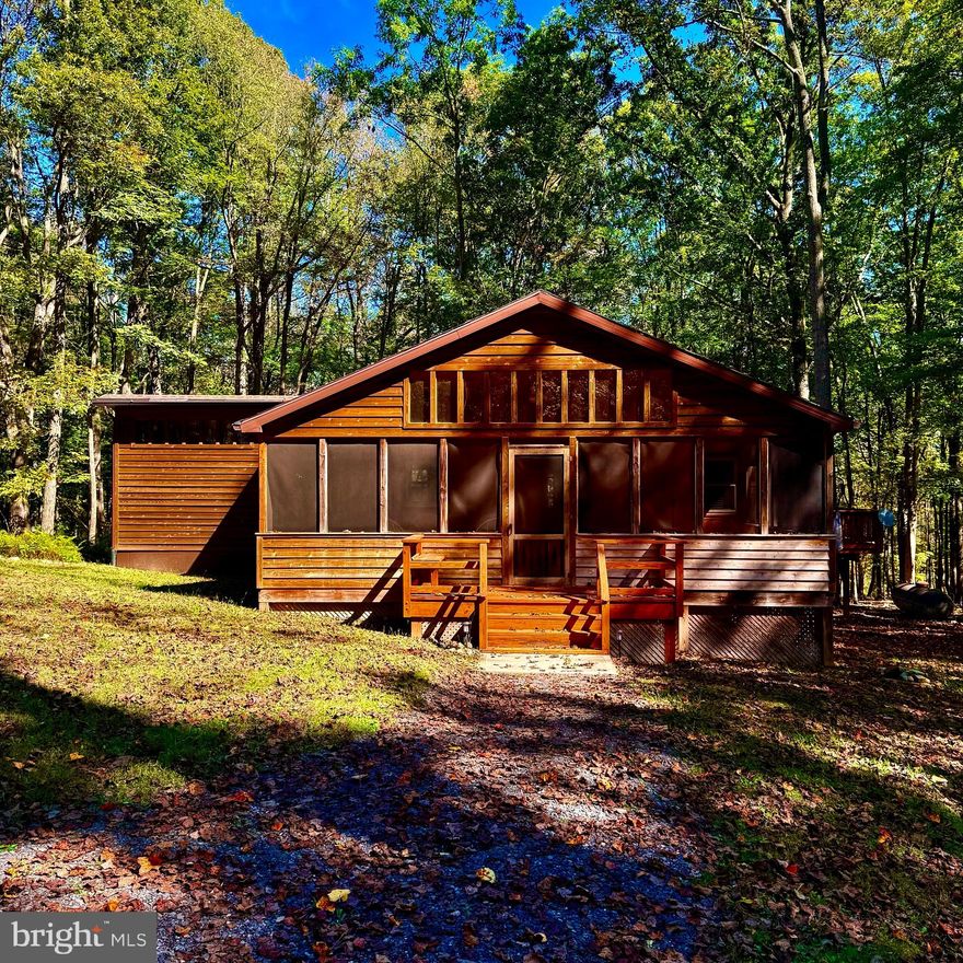 Have you been to West Virginia lately? If you find yourself driving through the scenic beauty of Hardy County, make sure to swing by and experience this charming 1983-built cabin for yourself. Tucked away on a level, private lot in the desirable Trout Pond community, this 2 bedroom, 2 bathroom retreat offers the perfect balance between rustic character and modern convenience. From the moment you arrive, you’ll notice how seamlessly this cabin blends with its surroundings. A large cedar-sided screened-in porch welcomes you, providing the perfect space to relax, sip your favorite drink, and listen to the sounds of nature. Additional covered porches make grilling, entertaining, or simply birdwatching a year-round pleasure. Step inside and you’ll find bright, airy living spaces with large energy-efficient windows designed to let in natural light and frame the wooded views, making you feel truly connected to the outdoors. This is an all-season home, ideal as a weekend getaway, full-time residence, or potential investment. With just a little updating, you can make it your own, or keep it as a turnkey mountain retreat ready for short-term rental income. Trout Pond’s HOA fee is just $180 per year, and the well-maintained community roads make access simple in every season. Nature lovers will rejoice in the location—only 5 minutes from Trout Pond Recreation Area, where you can enjoy fishing, swimming, hiking, and boating. For local flavor, head just 10 minutes down the road to Lost River for dining and farmers markets, or take a 20-minute drive to Wardensville for an organic farmers market, fine dining, and local grocers. HardyNet Fiber Optic Internet runs nearby and can easily be added to the property, though the current owner has chosen to keep this cabin WiFi-free as a way to disconnect from the fast pace of NOVA city life and fully embrace the serenity of the mountains. Whether you’re seeking a cozy retreat, an investment property, or a place to recharge and unwind, this cabin is a rare find in the heart of Wild and Wonderful West Virginia. Don’t miss your chance to see it—schedule an appointment today!
