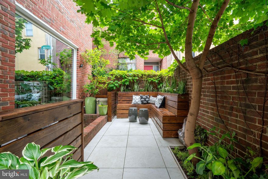 Welcome to your new home, tucked along a charming network of alleyways in historic Washington Square West. Whether you arrive via the garage—equipped with an electric car plug-in—or through the private, gated patio with custom built-in planters and a bench, you’ll feel at home at this serene retreat in the heart of Center City.

Stepping into the home, you are met by the charming living room, complete with a wood burning fireplace, built-in coat storage and bench, a massive picture window overlooking the patio and the lower level, and garage access. The living room and picture window open to the kitchen below, allowing natural light into the space. The kitchen has been tastefully renovated with classic white shaker cabinets, black granite counter tops, stainless steel appliances, and plenty of space for both dining and relaxing. A flexible nook located behind the kitchen is ideal for a home gym, study zone, or extra storage, and the half bathroom makes this level especially practical. There’s also a mechanical room and a separate storage room.

Upstairs, you’ll find three spacious bedrooms, each offering generous closet space and large enough to comfortably accommodate king-size beds. The second level features a bedroom with access to a private balcony, as well as a versatile open area currently used as an office. This space is enhanced by two floor-to-ceiling windows and a wall of built-in bookshelves, making it ideal for use as a den or library. A conveniently located laundry closet adds functionality to the area, while a full hallway bathroom serves both rooms.

The third floor is home to a generous primary suite, complete with floor-to-ceiling windows and ample closet space. This level also includes another full bathroom and an additional roomy bedroom.

At the very top, a roof deck provides space for outdoor dining, entertaining, and enjoying the city skyline.

Throughout the home, you’ll find terrific natural light, hardwood floors, recessed lighting, tasteful updates, loads of closet space, and central air. Garage parking and a quiet setting on peaceful side streets make daily life feel a little easier. All this, just a short walk to neighborhood staples like Whole Foods and Acme, and within minutes of Jefferson, McCall school catchment, and everything Center City has to offer.