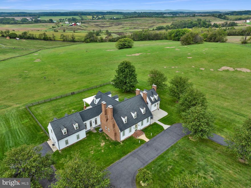Welcome to Retreat Brown Dog Farm! A truly one-of-a-kind replica of a c. 1750 Williamsburg Colonial, this remarkable estate combines the timeless elegance of historic design with the comfort of modern systems and amenities. With over 6,320 finished square feet with 7 fireplaces, step inside the slate-floor foyer and immediately be drawn to the panoramic mountain views framed by the expansive glass windows of the family room. This stunning space features vaulted, beamed ceilings clad in shiplap, hardwood flooring, and remote-controlled window shades, creating a perfect blend of charm and sophistication. The newly renovated gourmet kitchen is a chef’s dream—complete with a gas fireplace, cooktop, stainless-steel appliances, coffee and beverage bar with drink cooler, custom cabinetry, and both a walk-in and built-in pantry. Take the kitchen staircase upstairs and you’ll find a versatile bedroom/studio/office with a half bath. The main level offers multiple inviting gathering areas, including a formal dining room, living room, ​f​amily room, and carriage house each highlighted by its own brick fireplace. A full bath and library/game room add to the functionality and flow of the home.​ Accents of unique brick floors compliment the kitchen, orangery, and floor between home and carriage house. A grand double staircase leads to the primary suite, complete with its own brick fireplace, luxurious ensuite bath with jetted spa tub and shower, and a walk-in closet. The upper level also includes one additional bedroom, with its own character—with a brick fireplace and full bath, plus a laundry room for convenience. The carriage house features a fourth bedroom and full bath, ideal for guests or extended family. Downstairs, the rustic-style basement offers a recreation area, lounging space, workshop/storage room with cabinetry, laundry sink, and second washer/dryer hookup, with walk-out access to the grounds. Nestled on almost 22 picturesque and usable acres, the property enjoys sweeping mountains and pastoral views. Continue the existing farm lease or create your own equestrian facility, bed & breakfast, or vineyard—the possibilities are endless. A custom-built deer stand is already in place for outdoor enthusiasts. An Accessory Dwelling Unit has been approved and designed by Dorman Builders for a tenant house/in-law home. Meticulously maintained and rich with detail, Brown Dog Farm is more than a home, it’s an experience you must see to believe. Come see it for yourself!