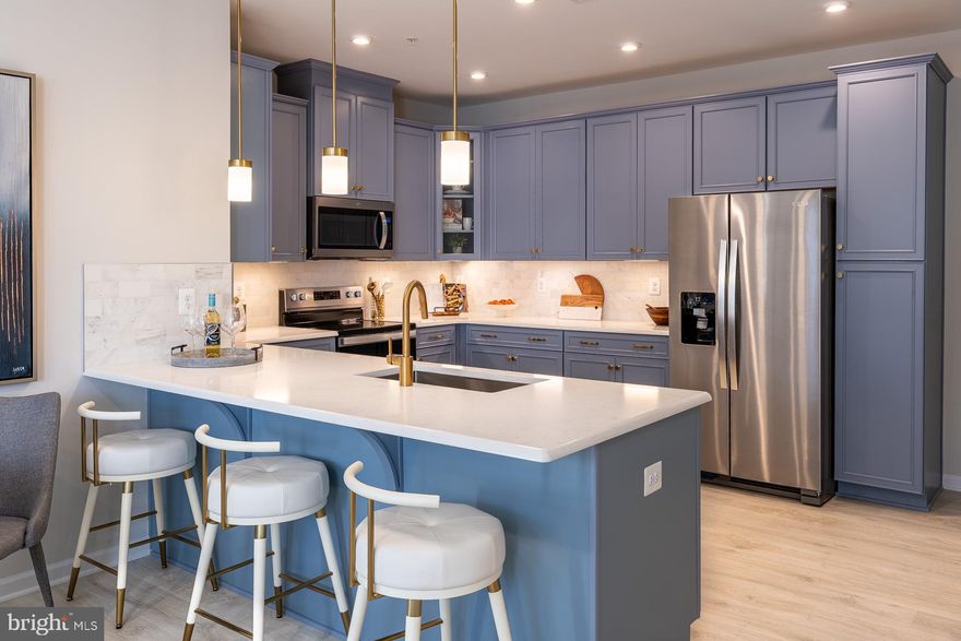 Welcome home to the Riva, a thoughtfully designed lower‑level, 2‑story condo with a 1‑car garage, nestled in the vibrant One Central community in Gaithersburg. From the moment you step inside, you’ll feel how this home blends comfort, style, and convenience in all the right ways. The open kitchen is truly the heart of the home—featuring abundant cabinetry, a designer tile backsplash, generous counter space, Whirlpool® stainless steel appliances, luminous pendant lighting, and beautiful quartz countertops that make cooking and gathering feel effortless. It flows seamlessly into the bright, welcoming great room, where natural light fills the space and creates a warm, inviting atmosphere. Just off the great room, a tucked‑away powder room adds everyday convenience. Upstairs, life gets even easier with a centrally located laundry room and a flexible layout that lets you choose what fits your lifestyle best: three bedrooms or two bedrooms and a loft. The primary suite becomes your personal retreat, complete with a spacious walk‑in closet and a serene bath offering a private water closet, dual sinks with quartz countertops, and a large walk‑in shower. This is a home designed to support your everyday moments—big and small—with ease, warmth, and style.