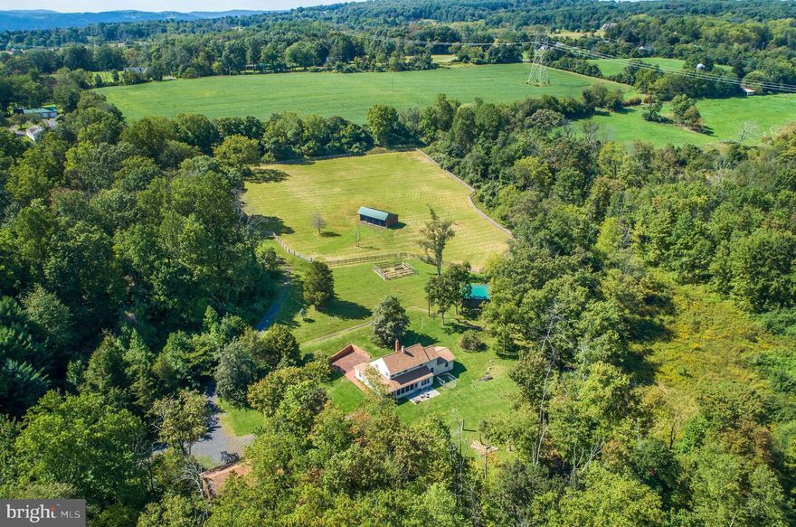 Looking for tranquility and a place to raise you 4 legged critters? This 16 acre piece of heaven in Upper Bucks could be a good fit. Built in 1978 with an addition and upgrades over the years, this efficient 2-3 bedroom sits nicely concealed from the road. Its spacious rooms include a living room with a handsome stone fireplace with woodstove insert, high ceiling and beams; country kitchen, central to this level with upgraded stainless appliances, radiant heat, tile floor and wonderfully large breakfast room with lots of windows; a 26x18 great room addition for ideal uses as a studio, gym, office or playroom; a utility room houses the newer high efficiency 4-Zone boiler; laundry area. A few steps from the kitchen and off the living room is what could be either a dining room or 1st floor bedroom. A full bath with shower stall completes the first floor. The primary bedroom upstairs is fully carpeted as is the second bedroom each with really huge walk-in closets. The hall bath has a tub/shower with tile floor. The screened in porch and stamped concrete terrace are welcoming resting spots. A short walk up the gently sloping lawn takes you to a garden site, fenced pasture with hydrant and beyond that on a knoll, the pole barn/3-sided run-in shed containing a horse stall with potential for 3 more. Another structure is a generous sized storage shed to accommodate any needed equipment as well as hay. Over half of the acreage is wooded with a wet weather stream running through it. In addition to the detached two bay garage with electric, there is a third bay built to house an RV or horse trailer. This property has been well loved by its current owners and they await the next stewards.