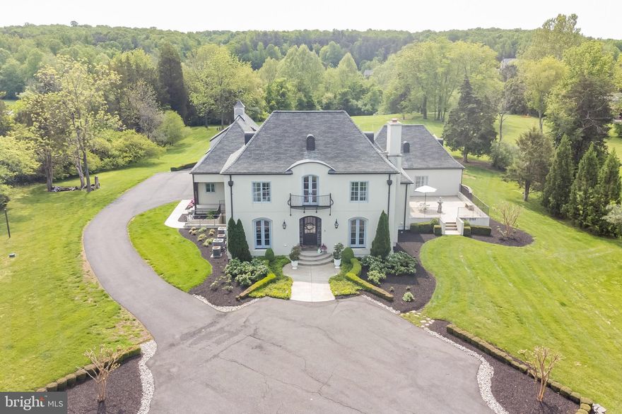 A rare opportunity to claim one of the region’s finest estate properties where you feel like you have been transported to a French chateau in the countryside! This one-of-a-kind custom built stucco home was designed by nationally renowned architect Jack Arnold and has been thoughtfully upgraded by the current owner/designer to look like it was torn out of the pages of your favorite home magazine. The stylish home, which is beautifully situated on 5.24 manicured acres in the coveted Seven Lakes neighborhood, features not one, but two large hardscaped patios – an entertainer’s dream! From the rear patio, overlook the vast private rolling green lawn which leads down to the lake. Toward the rear of the property is a gravel-lined firepit area – perfect for family bonfires. Apparent on arrival is the fact that no detail was overlooked such as the custom copper roofing vents, weather vane, Juliette balcony, meticulous landscaping & oversized custom French blue doors & windows imported from Canada. Moving inside the home, you will fall in love with the light-filled & airy open floor plan with 10-12’ ceiling height throughout, luxury materials & finishes. Main level highlights include: a stunning green lacquered library/music room, spacious formal dining room with wood-burning Rumford fireplace & European style mantle, large laundry room with additional refrigerator, mud-room area with custom cubbies/built-ins for coats, shoes & backpacks. The large living room features another wood-burning Rumford fireplace & three sets of French doors overlooking the east patio. For the gourmet cook or avid entertainer, you will love the top of the line Chef’s kitchen featuring Calcutta gold marble countertops and a walnut kitchen island, Wolf gas range with two ovens, stainless large farmhouse sink, hidden microwave drawer, 2 dishwashers & a Miele refrigerator which seamlessly integrate into the custom Graber cabinetry. The wine enthusiast will appreciate the humidity controlled butler’s pantry with storage for 180 bottles of wine. The grand main level master suite has a spacious & private sitting area, soaring cathedral ceilings (16’) & french doors leading to the back patio where you can directly step out and enjoy your morning coffee! The luxurious en suite master bath is where you will indulge in a spa-like experience with a large soaking tub & oversized marble shower with dual shower heads. His & hers marble vanities with Venetian mirrors & spacious his & hers closets complete this beautiful retreat. On the upper level, there are three spacious bedrooms - all of which have walk-in closets & two of which share a Jack and Jill style bath. A separate back set of stairs near the mudroom will lead to another private upper level- an enormous studio/office space over the garage, which could also be a 6th bedroom, with plumbing accessible for a bathroom area in what is currently a large storage closet. More living & entertaining space can be found in the fabulous & recently finished lower level, featuring beautiful light oak flooring throughout. A large playroom/workout room has natural light & mat flooring. In the main area, you’ll find modern industrial flair with a built-in bar complete with quartz countertops, built-in banquette, marble backsplash, wine fridge & mid-century modern accent lighting. A large bedroom with 2 queen beds is perfect for in-law’s, au-pair or just holiday guest overflow. The full bathroom features a frameless shower & a custom vintage style sink & lighting. In addition, there are two ample storage rooms for all your needs. Finally, the cherry on top is an amazing & brand new, state-of-the-art Dolby Atmos movie theatre! You’ll never go to the movies again once you experience a private screening like this…a new level of comfort with reclining tiered seating, art deco gold leafed sconces, ceiling cove lighting and luxury Stark carpet. Make this spectacular & truly custom dream home your reality!