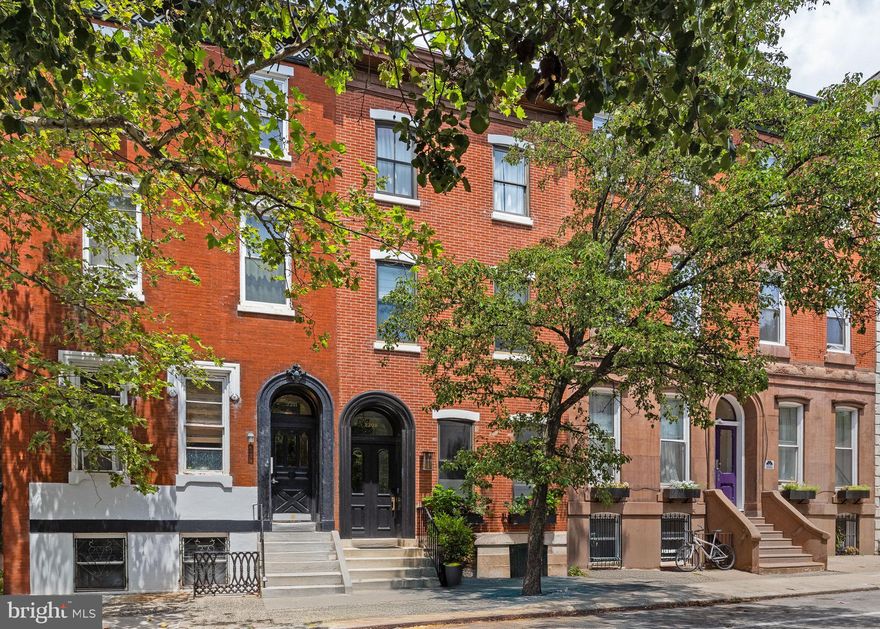 Picture-perfect historic details alongside impeccable finishes make for an absolutely stunning residence, where the interior’s beauty is rivaled only by the private roofdeck’s 360-degree views. The extensive renovation preserved original random-width pine floors, curved banisters, select millwork and plaster crown molding in 12-foot ceilings and used dark stained floors, crisp white walls, black doors with contemporary Emtek glass knobs, and recessed lighting paired with statement decorative fixtures to lay the foundation for its perfect old-meets-new aesthetic. The updated floorplan on the main level offers a living room anchored by a gas fireplace with alabaster mantel, powder room and an ample dining area that flows into the expansive kitchen with French doors to the secluded rear patio. Five bedrooms–including an exquisite primary suite and a large secondary suite–a third full bath and laundry are spread across the upper two floors, as well as a large wet bar with wine fridge and generous counter and storage space on the way to the roofdeck. Every detail throughout the house was carefully chosen, and nowhere is that more evident than in the kitchen, which is as gorgeous as it is functional: Legacy Crafted cabinetry that runs to the ceilings, including a full wall span; coffee station; a beverage station with prep sink convenient to the patio; Vermont Danby marble slab backsplash, countertops and island with seating for four and dramatic bell pendant lighting; Perrin and Rowe faucets and potfiller; cabinet hardware by Emtek and top-of-the-line appliances including a 36-inch Sub Zero fridge, Wolf 36-inch six-burner range and Miele steam wall oven. Upstairs the two suites are separated by a large hallway laundry closet with folding station and fun mosaic cement tile walls alongside a large linen closet. The luxurious rear corner primary suite occupies much of this floor, offering a massive bedroom with three side windows–providing gorgeous natural light with maximum privacy–a walk-in closet with custom organizers and an en-suite with two exposures; white herringbone porcelain tile floor, full-wall backsplash and surround in the oversized walk-in shower; oversize pendant over the stunning soaking tub; and marble double vanity with pivoting mirrors. The suite on the other end of this floor has an extra-large bedroom, double closet and resort-inspired bathroom with a deep soaking tub with serene blue full-wall surround, custom open shelving and another large closet. The three remaining bedrooms are on the third floor, together with a hall bath beautifully appointed with mosaic cement tile wall and surround in the walk-in shower. The expanded wet bar and notable level of privacy given the height of the neighboring properties make the Trex roofdeck all the more enviable. The basement offers ample storage space and a second set of laundry machines. In the Greenfield catchment, the sought-after Rittenhouse Square location provides the ultimate Center City living experience.