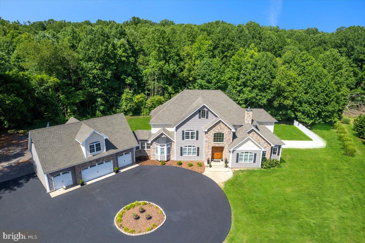 IMPRESSIVE, IMMACULATE, STUNNING ESTATE IN NORTHERN CALVERT COUNTY! This show-stopping residence SHINES with over 10,000 finished square feet upon 10 acres of scenic, private, wooded property.
Discover a sanctuary of style & sophistication within this incredible home adorned with a spectacular stone front & cedar shake vinyl siding, surrounded by picturesque landscaping. The circular driveway leads to the path of a stamped & stained concrete sidewalk. You will be greeted by a soaring 8' tall double door entry. The custom designed front double doors are fiberglass insulated, stained & marine varnished to give a wonderful wood appearance, while maintenance is a breeze! Indulge in the sheer comfort and elegance of the interior, where 2 x 6 construction & upgraded insulation choices ensure a cozy atmosphere in every room. The main level showcases the ultimate, enormous owner's suite with double door entry to both the primary bedroom and bathroom.
The culinary enthusiast will delight in the gourmet kitchen, a masterpiece equipped with top-of-the-line KitchenAid appliances, custom designed soft-close cabinets and granite countertops. Don't miss the thoughtfully placed pot filler above the 6-burner cooktop with a griddle on the end! Admire the elegance of the rounded archways & cathedral ceiling in the kitchen nook, creating a welcoming space to enjoy everyday meals or entertain guests. Entertainment is effortless with the main level custom wet bar area, featuring a wine rack, refrigerator, and under cabinet lighting. Move seamlessly into the grand family room with a two-story stone fireplace, an extraordinary coffered ceiling, and custom millwork columns, offering a perfect setting for family gatherings or cozy evenings by the fire.
Retreat to the luxurious Owner's Bedroom with LED recessed lighting, a tray ceiling, dual ceiling fans, and an en-suite bath adorned with 24x24 tile, dual vanity sink cabinetry, granite countertops. The deep & oversized soaking tub features designer plumbing fixtures, a removable wand & tiled bath surround. A 5x5 arched fixed picture window above the soaking tub provides lovely wooded views. The owner's shower is tiled to the ceiling with decorative listello tile trim detail, dual shower heads, a removable shower wand, rain shower head, a tiled bench and frameless glass enclosure. Revel in the abundance of storage space with two walk-in closets. The Owner's suite windows face the private & mature hardwood out back. The sitting area also has a plumbing rough in for a future wet bar! This space is the perfect blend of functionality and elegance.
Explore the finished basement with 9 ft ceilings. Enjoy the tranquility of the screened-in porch & maintenance-free composite deck, or host outdoors on the expansive patio. The spacious garage appeals to any car enthusiast with room for 4 cars and additional space for a potential apartment or office above. From the charming plantation shutters & crown moldings to the marvel that is the remarkable rounded staircase, as well as thoughtful details (like the fire suppression system) this home offers a blend of luxury and practicality. Embrace the serene oasis that is 10 acres of privately owned land in Northern Calvert County. This home is located off of a cul-de-sac & set back from the road, complete with a fenced area for added privacy & safety. This home also features premium systems & mechanicals - dual zoned HVAC with gas back up heating, a 500 gal propane tank & a best available technology nitrogen septic system for efficiency. This home is a harmonious blend of modern amenities and timeless elegance.
Located just minutes away from parks, hiking trails, nature preserves as well as shopping, dining, entertainment and TOP RANKED schools as well as major commuter route 4, the location cannot be beat! 1915 Owensville Court is an elite home and property, well built and designed with the highest level of detail. Schedule your showing today!