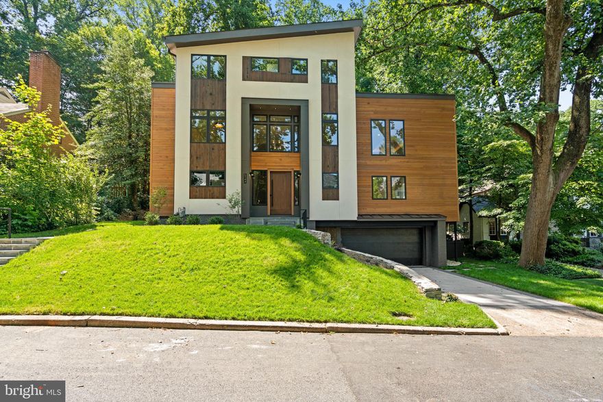 Discover the pinnacle of contemporary luxury with the newly constructed home by renowned Property Alchemist LLC, located in the tranquil Kent neighborhood of Washington, DC. This architectural gem draws its inspiration from soft modern movement, boasting a facade of sleek stucco paired with rich wood and framed by elegantly laid natural stone paths and terraces. The entry level exudes a welcoming warmth, illuminated by abundant natural light that enhances the pristine oak wood floors and highlights the dramatic two-story foyer. Designed for both comfort and entertaining, this floor features a family room complete with a chic serving station that includes a wet bar, mini-fridge, and ice maker, while French doors open to a covered rear terrace. Accommodations on this floor include two luxurious bedroom suites, each with private bathrooms, making it ideal for multigenerational living with the convenience of an elevator accessing all levels. Further enhancing its allure, there is a spacious mudroom/laundry room equipped with ample storage and a utility sink. 

A glass-paneled staircase with vertical slat detailing ascends to the second floor where the expansive open concept floor plan unfolds under soaring ceilings and generously scaled formal living spaces. Here, a sophisticated living room features a stunning two-sided architectural fireplace shared with the formal dining room, beneath a stunning and backlit tray ceiling designed for sublime entertaining. The state-of-the-art gourmet kitchen is a culinary showcase well-appointed with custom cabinetry, quartz countertops and backsplash, and includes a beverage refrigerator, an ice maker, and high-end appliances from SubZero, Dacor, and Bosch. Adjacent to the kitchen, a generous butler’s pantry offers additional storage along with wall ovens and a sink. The kitchen seamlessly connects to the expansive and sunlit breakfast and family rooms, with light from southwestern facing oversized windows. There is also the added convenience of a sizable office on this floor. The tastefully designed hardscape terrace is perfect for entertaining, featuring ample table space for dining and a cozy seating area with a firepit, creating an inviting atmosphere for gatherings. 

The top floor is flooded with sunlight from three skylights and hosts three en-suite bedrooms, including the luxurious primary suite. Accessed through double doors, primary bedroom offers exceptional scale, high ceilings, and a walk-in dressing room with abundant built-ins and a center island for storage. The spa-inspired primary bathroom is illuminated by skylights and equipped with dual vanities, ample storage space, a large soaking tub, two water closets, and a walk-in shower with a shower bench and multiple shower features including rainfall, standard, and handheld settings. Both additional bedrooms on this floor are spacious and include large closets and en-suite bathrooms. Completing this exquisite home is an oversized temperature controlled two-car garage with additional storage space, ensuring every aspect of this home is as functional as it is beautiful. This property represents a masterful blend of luxury and sophistication, designed to offer an unparalleled living experience in one of Washington, DC’s most sought-after neighborhoods.