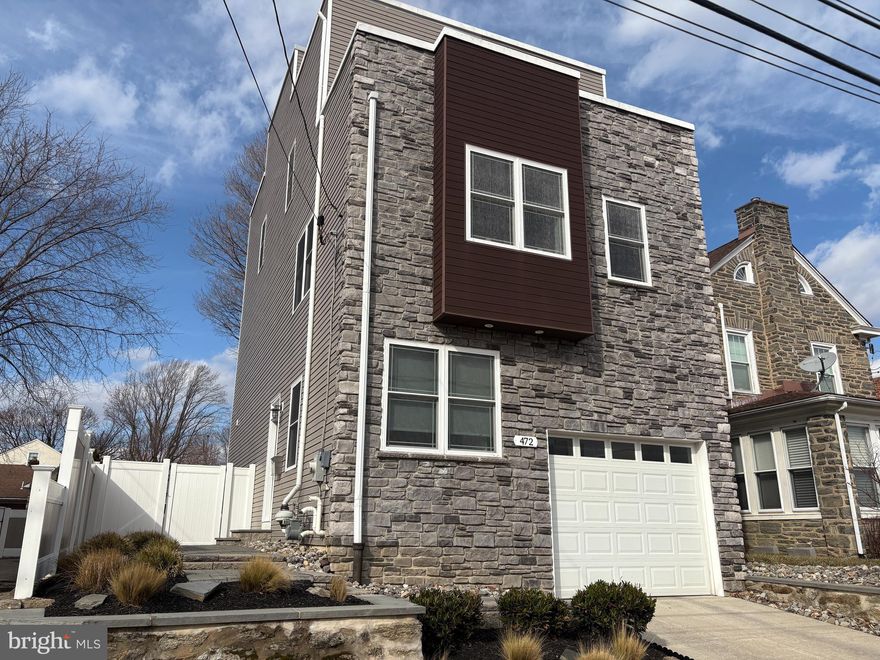 A house so cool…. other houses wish they could be just like it.  But they can’t because this one is in a class of its own.  Welcome to 472 Cinnaminson Street; built in 2017 with careful craftsmanship and an eye toward style.   Situated within easy walking distance to the Ivy Ridge commuter train, a playground, the Gorgas Lane trailhead to Wissahickon Park, shopping and restaurants, this well-established neighborhood feels like small town while the startlingly big and fully fenced back yard gives suburbs!   After taking in the beautiful exterior with its Ledge Stone frontage, wood accent bay and EP Henry paver walkway, you’ll enter into the Main Level foyer to find an immaculate, modern interior designed for today’s lifestyle.  Oak hardwood floors grace this and all of the upper levels. The foyer offers a secure steel front door with Mission-style stained glass, access to the one car garage and a coat closet with California Closet system.   There are two bedrooms on this level, both currently used as home offices.  The back bedroom is the larger of the two and features a walk in California Closet plus sliders to the EP Henry patio and expansive back yard... a rare find in this neighborhood with approximately 2000 sq feet of  private back lawn.  The hall bath, with its quartz accents and oversized shower, offers direct access to this bedroom as well as to the foyer hallway.   The 2nd Level is one large open space with light-filled windows on every wall.   There is the Dining Area with coffered ceiling which blends into the central kitchen featuring an 8 foot island and built-in butler pantry with granite countertops.   Soft-close, solid wood Shaker cabinets provide ample space for storing all your kitchen needs.   Stainless steel appliances include gas range with griddle burner, brand-new GE Profile refrigerator, an undermount kitchen sink with disposal, dishwasher and gooseneck faucet and a built-in microwave.  A large Living Room area completes this level.   The 3rd Level is home to the Primary Suite with walk-in California Closet and ensuite bath.   The Primary Bath features a barn door, double sink with granite countertop and oversized shower.   The 4th Bedroom is also on this level and faces the front of the house, featuring its own private balcony and California Closet.    A hall bath with tub/shower plus the laundry closet complete this level.   Get a bird’s eye view and a great suntan on the roof deck where you’ll not only get a city skyline view, but will also get to see fireworks from every angle!  The roof deck is ready to rock with Sonos speaker wiring.   But wait, there’s more!   The fully carpeted basement provides a large recreation or family room plus storage and utility areas.   Home has dual heating and cooling zones, 9’ ceilings and 2 years remain on tax abatement.  Buyers will receive a one year HSA home warranty at the time of settlement.