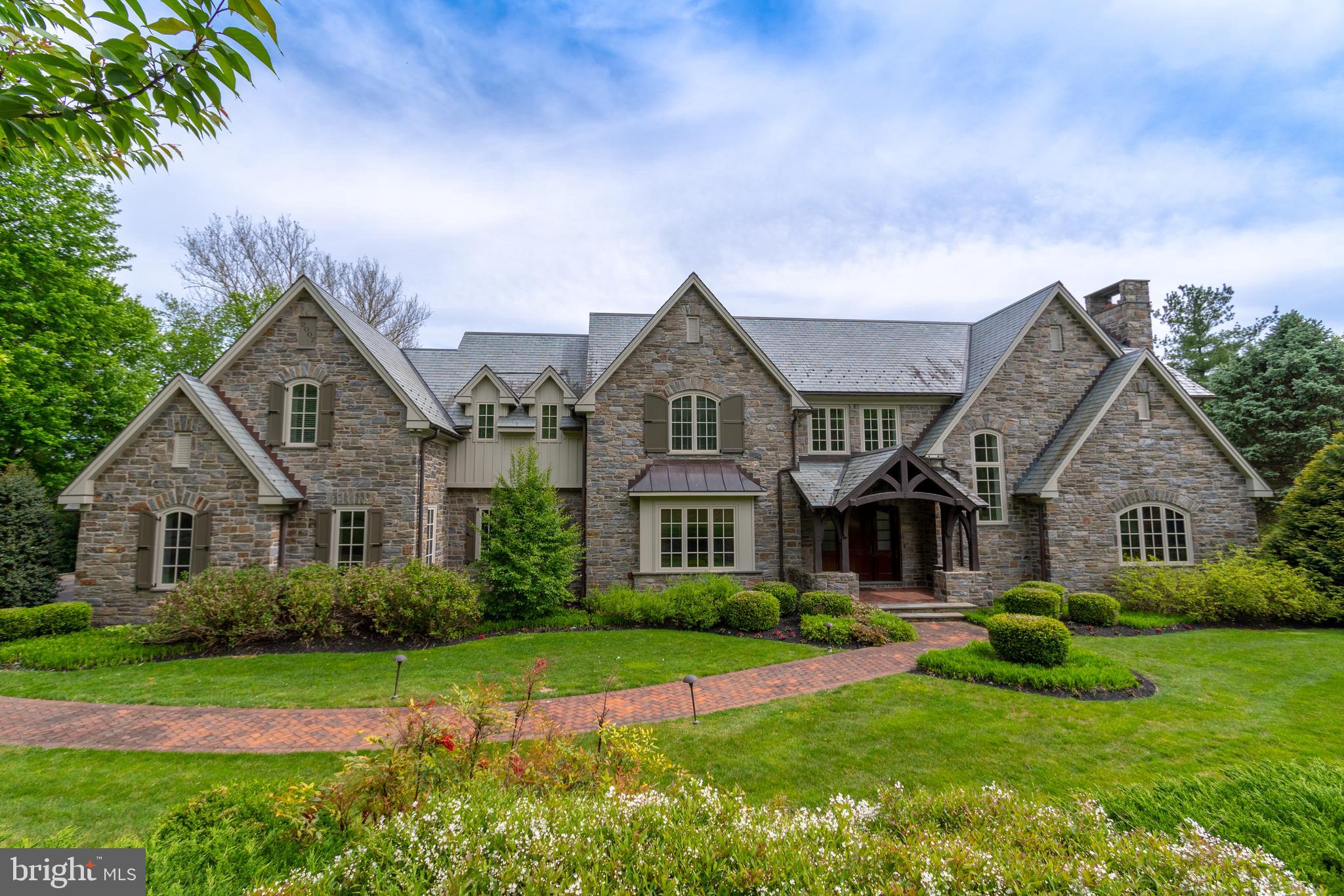Introducing this elegant stone estate situated on almost 2 acres of beautifully manicured grounds. This stunning home is luxury at its finest offering every amenity & feature you could ever want. The custom home greets you w/stone pillars, private driveway, stone walls accenting the gardens, paver patio walkway to the front entrance & beautiful slate roof. This luxurious home features h/w floors throughout, sunlit rooms w/natural light, coffered ceilings, wainscoting, recessed lighting, over-sized arch doorways, beautiful woodwork details & trim. Enter through a covered porch to a grand Foyer that truly sets the tone for this charismatic home. The 2 story Foyer features h/w floors, crown molding & wainscoting. The Foyer opens to a large sunken, sunlit Family Room w/impressive views of the picturesque grounds & patio. The Family Room features a fireplace w/14 foot stone wall & wood mantel that is sure to be a focal point on those cold wintery nights. This room has a coffered ceiling & double door opening to the large flagstone patio. Enter the Kitchen through an over-sized arch doorway flanked by glass walls from the Family Room. The show stopping Kitchen is truly unforgettable w/custom cabinets, fridge & full size freezer, wolf oven, gas range, granite counters, over-sized island w/cabinetry & sunlit Breakfast Room. The Breakfast Room is surrounded by windows allowing natural light to pour in & access to the large patio. The patio has a built-in grill & fridge. Enjoy the beautiful views of the in-ground pool while entertaining on the Patio or barbecuing. The formal Dining Room has a coffered ceiling, wainscoting & access to a spacious Butler's Pantry. The Butler's Pantry has granite counters, sink, ice maker, wine fridge, glass cabinets & drawers. This layout is perfect for entertaining, whether it is small intimate gatherings or large holiday parties. Walk down the hallway to a large Den w/crown molding, door access to the patio & walk-in closet. Across the hall is an extraordinary Study w/ double door arch entrance, wood walls, gas fireplace w/beautiful wood details & mantel, herringbone pattern h/w floors, coffered ceiling, custom built-ins & custom wood ladder. Completing this room is a large window seat overlooking the front gardens. On those rainy days, park your car in the 3 Car Attached Garage & access the home through the Mud Room. The Mud Room features custom cubbies w/storage. The built-in bench is perfect to use when you need to take off your winter attire & boots. This room w/its abundance of storage & garage accessibility is a must have for any family. The Mud Room also gives access to the covered Breezeway w/stone walkway that leads to a 2 Car Detached Garage w/ Bonus Room & half Bath. In the main house, walk up the Foyer staircase or back staircase to reach the Upper Level. The spacious Master Bedroom Suite features a tray ceiling, h/w floors & fireplace flanked by windows. The Master Bath will transport you to a spa like atmosphere w/tile floor & custom inlay, 2 sinks w/custom cabinets & granite counters, a sunken jacuzzi surrounded by granite, water closet & large tile stall shower w/bench. The Master Bath also gives access to an exquisite Master Walk-In Closet w/custom built-ins, double door closet & large island w/drawers & granite counter. This Level also features a second Master Bedroom w/Sitting Room & full Bath, 3 additional Bedrooms that all feature ceiling fans & spacious walk-in closets w/built-ins, 2 full Baths, hall linen closet & Laundry Room w/sink & built-in shelves w/large counter perfect for folding laundry. This home is truly a one of a kind home. Do not miss this opportunity to own a home in the great neighborhood of Pennock Woods that has so much to offer in schools, restaurants parks and the ability to walk to Meadowbrook Train Station. This home was designed for year round entertaining with modern luxuries and old world charm! See attached for description of Finished Lower Level!