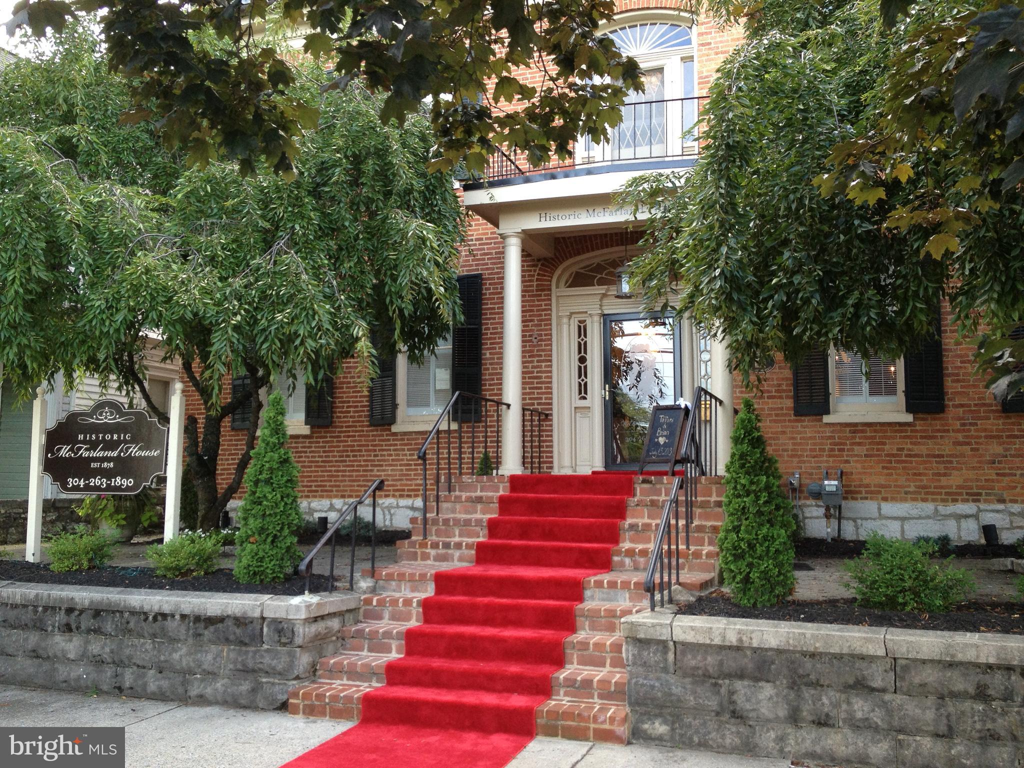 Rare opportunity to acquire an exquisite Georgian architectural masterpiece & community landmark- The beloved historic "McFarland House" mansion- circa 1878. Prominently located with Queen Street frontage in the historic district of Martinsburg. This grand estate boosts over 9,000 sq ft of living space coupled with an addition approx. 7000 sq ft back yard oasis. The interior has 17 rooms- comprising of 6 bedrooms, adjoining atrium ballrooms with moving glass wall system to create an expansive approx. 1800 sq ft spectacular space, multiple parlors, bars, kitchen fully retrofitted for commercial use, upper kitchenette, 2 full bath, 2 half bath, laundry room, dual interior staircases. The rear outdoor space features a large covered pavilion with flagstone floors, brick walk ways, brick & stone retaining walls, lush landscaping with electrical pre-wiring and lawn wedding arena - Extensive renovation continue to evolve on this property yet always managing to preserve the integrity of its grand architectural details - complete with crystal chandeliers , flagstone floors, hardwoods, stamped concrete, handcrafted moldings, 10+ foot ceilings, original plaster walls, grand marble bathroom, period replicated custom woodwork, etc. Not to forget the modification to allow for full handicap accessibility to main floor… Originally constructed by local prominent businessman and entrepreneur Alexander B. Parks, this landmark exudes timeless charm and is a benchmark of Martinsburg’s rich history and character. Though the property gained renowned recognition when proprietors William and Jane McFarland took possession and operated a catering business from their home. Their business success attributed to its local reputation of exquisite culinary offerings and as a favored gathering location- Hence the estate became known as the “McFarland House”. Since 2007, the current owners have embraced and honored its history, as they have committed to continue the legacy offering The McFarland House as a wedding venue, banquet, event location and gourmet dining experience. The McFarland House offers a unique opportunity to own a piece of history. It can easily be converted back to an amazing residence. The location, reputation and heritage of the property sets the groundwork for endless possibilities.