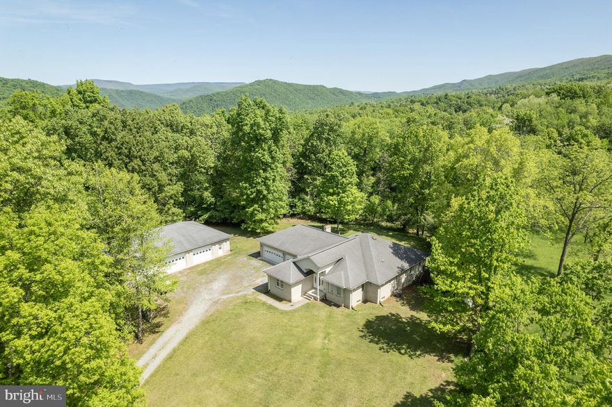 This Beautiful West Virginia estate, nestled on Harman Hills Rd, boasts 3 bedroom, 3.5 bath and and est. 2,184 finished square feet just on the main level!! This spacious one level living rancher, conveys an open layout from the kitchen to the living room and leading into the vast sun room.  The primary bedroom is located right off the living room, and has ample space for whatever furniture you could throw at it! The primary bedroom is conjoined with the primary bath, and coveys a double vanity, private bath, and walk in closet! Walking down the hall way, you'll find an office with plenty of natural light along with beautiful mountain views, two more bedrooms, and another full bath. The full unfinished basement hosts another est. 1944 square feet of open layout for your future man cave with a dry bar, living room, 2 recreation rooms, utility area, along with another full bathroom. If the man cave in the basement wasn't enough, how about the three car attached garage, if not, i'm sure the detached  6 car will suffice. The attached three car garage supplies ample storage for vehicles, tools, overflow from the home, as well additional attic storage. The 6 car detached garage is the epitome of a mans dream! The right bay is completely insulated and gas heated for your winter projects with more attic storage! The left two bays are unfinished, but still has lighting and electric receptacles all throughout. Last but not least, this country beauty sits on 6.16 acres and is surrounded by panoramic views of farms, pasture land and mountainous landscape. Don't miss this opportunity, there is reason why they call it Almost Heaven!