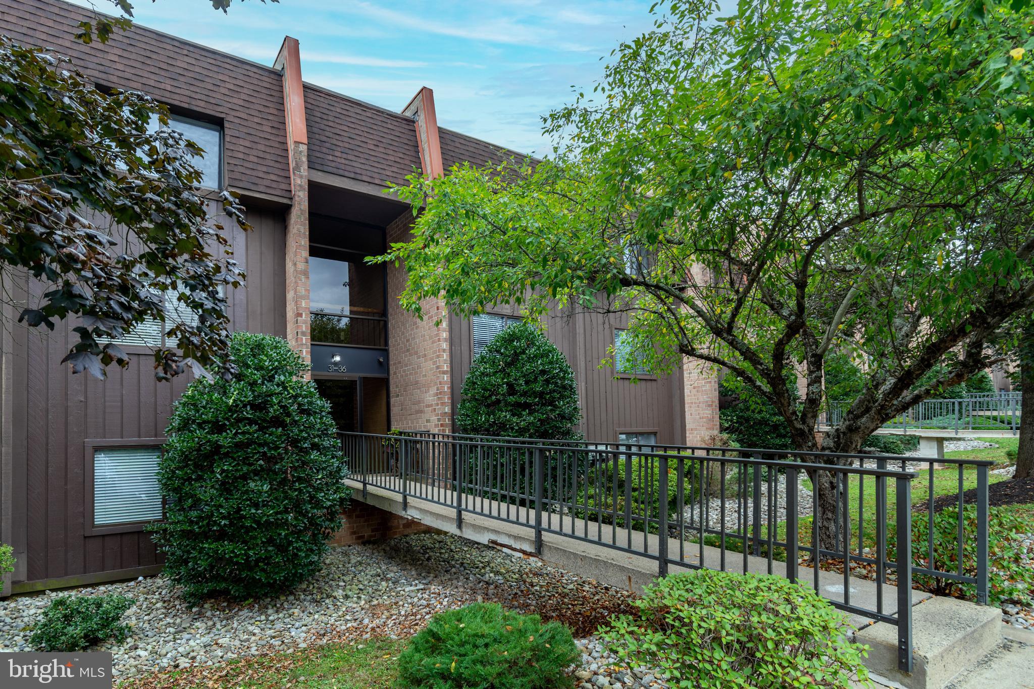 Tucked into the wooded edge of Solebury Township, this Rare Find, a 1470 square foot, two-bedroom home at the Hermitage Condominium is one of only seven two-bedroom units in this 49-unit complex. Standing apart not only in size but in orientation, it overlooks the protected Aquetong Spring Park. The park itself, sacred to the Lenni Lenape Nation and now stewarded by Solebury Township, features nine hiking trails, a limestone spring, and a waterfall that is accessible directly from the condo grounds via a short trail. A dramatic 22-foot wall of floor-to-ceiling glass opens to a matching 22-foot balcony, framing uninterrupted views of the 48-acre parkland below. Only one other two bedroom unit in the development shares this elevated west-facing vantage, ideal for sunset watching and seasonal color. Inside, the home has been thoughtfully renovated in the Japandi style, a fusion of Japanese minimalism and Scandinavian warmth. The kitchen features custom rift white oak cabinetry with sleek cabinet edge pulls, under counter lighting, quartz Bianco counters with a waterfall island, all new stainless appliances and a stainless farm sink and integrated wood-wicker accents. A brand new concealed stacked Miele washer and ventless dryer are tucked into matching cabinetry. The newly renovated bathroom continues the aesthetic with earth toned tile flooring, teak vanity, new fixtures and a deep soaking tub with subway tile surround. The main bedroom has a big walk-in closet and lots of space for a vanity too. The second bedroom offers a large closet and has room for a desk. Throughout the unit, newly installed COREtec Premium Blended Cocoon vinyl plank flooring complements the neutral palette, while oversized closets and a smart HVAC system enhance comfort. The layout is open and light-filled, with no neighbors above and the community includes a large saltwater pool, assigned parking near the entrance, and ample guest parking. With downtown New Hope and Peddler’s Village just minutes away, this incredible home offers quietude, design integrity, and easy access to both nature and culture. Just move in it's all ready for you!