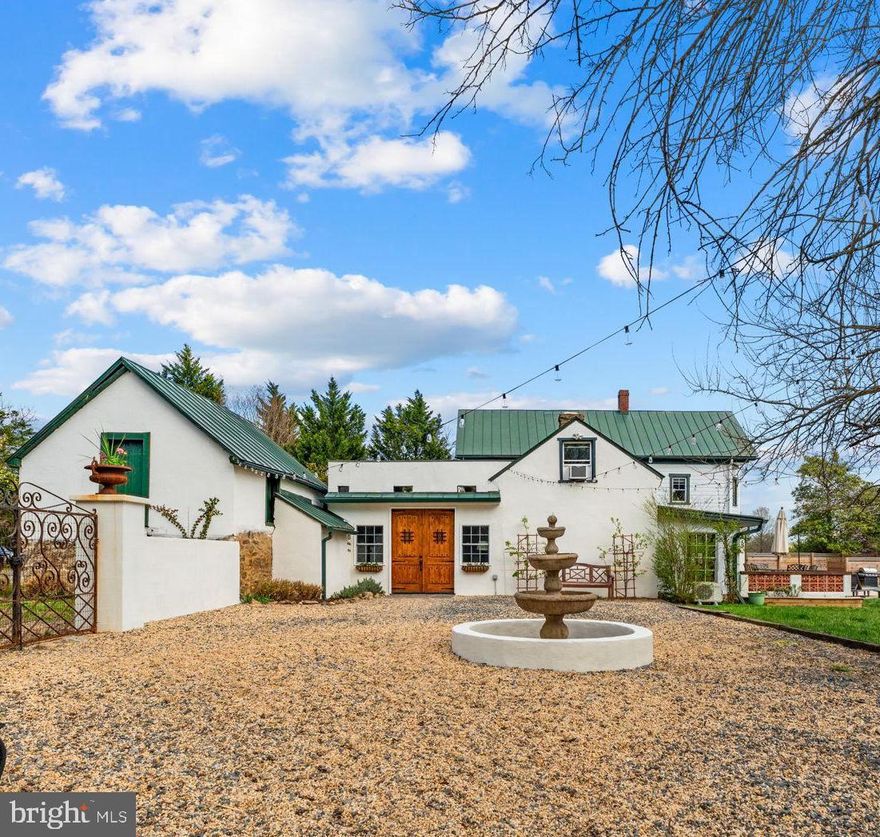 Enter through wrought iron gates into a private gravel courtyard centered by a tiered stone fountain, where wood front doors framed by pear trees welcome you to this European-inspired farmhouse set on just over 2.5 acres in Marshall, VA.

Perfectly located just across from Northern Fauquier Park, and minutes to I-66, downtown Marshall, Middleburg, and The Plains.
Offering 3 bedrooms, 2.5 baths, a pool, and a detached office/studio for added flexibility, with nearly fully fenced grounds, fully useable acreage, and the ability for animals.

Inside, original stone, exposed beams, and hardwood floors across the first two levels are complemented by artisan tilework and chandeliers imported from France.

The kitchen is anchored by original stone walls and exposed beams overhead, centered around a warm wood island. GE Cafe appliances and light stone countertops blend seamlessly with custom cabinetry, while a deep farmhouse sink looks out over the dining room. Every detail, from the patina of the wood to the artisan tile underfoot, grounds the space in both function and beauty. Just off the kitchen, a pantry/bread kitchen adds old world charm and utility with butcher block counters and open shelving.

Just off the dining room, a spiral staircase leads to the rooftop deck for inviting slow evenings under the stars.

A sunroom with Spanish tile floors and fully opening glass doors extends living seamlessly to the pool and patio, where planter boxes line the space—creating a true gardener and chef’s haven, perfect for fresh herbs, seasonal blooms, and outdoor dining.

Additional features include a finished attic, office space, a duck run, and two run in sheds.

Major systems have been updated within the last two years, including appliances, a water filtration system, and a tankless hot water heater.

Furniture is available for purchase.