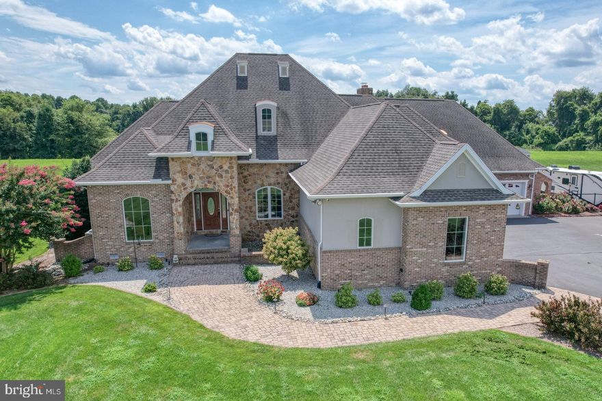 Rare opportunity to assume a 2.375% interest rate - inquire with Listing Agent today! Custom-built 3BR, 3 Full BA, 2 Half BA stone-front  home in a quiet, upscale neighborhood. The grand foyer opens to a light-filled, open floor plan with spacious formal dining, a cozy family room, and a front-facing office with nearly floor-to-ceiling windows. The gourmet kitchen features custom Bertch soft-close cabinetry, granite countertops, oversized island with prep sink and wine cooler, GE stainless appliances, 6-burner propane stove with griddle, pot filler, built-in oven, convection oven/microwave, warming drawer, heated food box, and pantry with built-in organizer.

The sunlit living room offers surround sound, floor-to-ceiling stone fireplace (propane/wood), and multiple windows for abundant natural light. The first-floor owner’s suite includes tray lighting, two custom walk-in closets with built-ins, oversized tile shower with rain head, whirlpool tub, dual vanities, and a private bedroom retreat. A second main-level bedroom includes its own full bath, plus there are two half baths on the main floor. Upstairs, find a spacious bonus room with full bath.

Enjoy year-round comfort in the 8x20 enclosed rear porch. The home boasts two heated/cooled attached garages with space for three vehicles, a concrete pad with 50-amp RV hookup, underground irrigation, programmable sprinkler system, outdoor custom lighting, and wrought iron fenced backyard with double gate access.

Exterior features include a built-in grill island with fridge, patio, fire pit hookup, fountain garden hookup, and professional hardscaping. Utility highlights: encapsulated crawl space with dehumidifier, tankless hot water heater, reverse osmosis, water softener, central vacuum (with kitchen kick-toe), and full security system with cameras, DVR, and ADT monitoring.

Truly one-of-a-kind—schedule your private tour today!