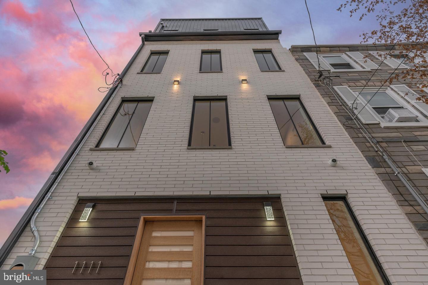 Welcome to 1111 Dunton Street, an exceptional 18-foot wide home built in 2021, spanning 2,700 square feet in Northern Liberties/Fishtown. This 4-story residence features 4 bedrooms, 4 full bathrooms, and a fiberglass roof deck. The seller is prepaying one year of parking at a lot at the end of the block, providing immediate parking convenience.
The spacious foyer on the ground floor leads to a full bathroom, coat closet, storage, a versatile bedroom, and a fenced-in backyard. The second level hosts an eat-in kitchen, boasting an 8-foot Carrara island with a waterfall edge, white upper and matte black lower cabinetry, a subway tile backsplash with a matte black pot filler, and a high-end Wolf appliance package with an induction cooktop. Adjacent is a spacious living room with tray ceilings and sliding glass doors opening to a private deck.
The third level is dedicated to the master suite, featuring a large bedroom, a walk-in closet, and a private full bath with a freestanding soaking tub, a large shower with matte black fixtures, marble finishes, and a double vanity.
The top floor includes a laundry room, a hall bath, and two en-suite bedrooms, each with large windows, ample closet space, floating vanities, and sleek lighting. A dry bar with a wine fridge precedes the private roof deck, offering unobstructed views of the Center City skyline and the Ben Franklin Bridge.
Benefit from over 6 years remaining on the tax abatement, ensuring significant long-term property tax savings. Please note there is no builder's warranty on this property. Located just one block from a vibrant array of restaurants, bars, and nightlife, with easy access to highways and bridges. Local hotspots include The Filmore, Frankford Hall, and La Colombe. Schedule your tour today.