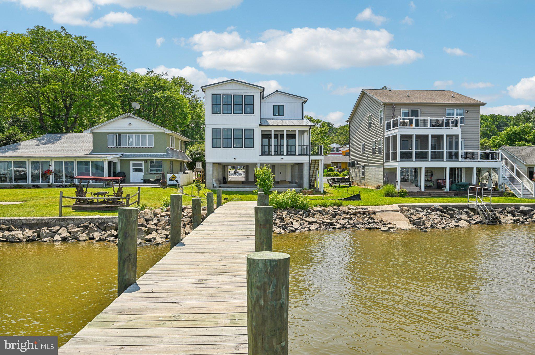 Waterfront Luxury New Construction just in time for SUMMER! Enter through double-door front entry to a thoughtfully designed space seamlessly blending style & function. Modern open concept luxury floorplan w/opulent finishes, high ceilings, & abundance of natural light. Home features an array of windows to enhance its waterfront views and create a bright, airy ambiance throughout. 5 spacious bedrooms, thoughtfully designed for comfort and luxury. The owner’s suite is a sanctuary of comfort and elegance, featuring soaring ceilings that create an open, airy ambiance designed for ultimate relaxation, complete with dual walk-in closets, offering generous storage & organization. Opulent owner’s bath provides a spa-like experience with premium finishes & a tranquil atmosphere. Enjoy a sun-drenched sitting area, flanked by windows that offer panoramic views of the North East River. A separate ensuite offers a private retreat, complete with a dedicated full bath, ensuring convenience and comfort for guests or family members. The additional bedrooms are generously sized, offering ample closet space and large windows to maximize natural light. Home features 2 luxurious spa baths w/ walk-in Roman-style showers, premium imported tiles, and elegant fixtures. A gourmet chef's dream, this kitchen is a harmonious blend of functionality and sophistication. It features imported, custom-designed cabinets w/ample storage, complemented by stunning quartz countertops w/show-stopping waterfall island & professional quality appliances including a WOLF gas stove top w/built-in steamer. Seller will provide comparable refrigerator, microwave and oven. Walk-in pantry and prep station, ideal for those who love to cook. The centerpiece is a sleek farm sink paired with premium fixtures. Floating custom imported Asian inspired cabinets add a touch of modern elegance, while the open layout seamlessly connects the living and dining areas, making it perfect for culinary adventures. Designed to captivate and impress, the living areas feature an open concept layout with an emphasis on breathtaking views of the North East River. The great room boasts expansive, window-flanked walls that flood the space with natural light and create a seamless connection to the outdoor surroundings. A covered main living level deck extends the living space, perfect for alfresco dining or enjoying serene waterfront sunsets. Anchoring the room is an elegant electric fireplace with a handcrafted wood surround, serving as both a focal point and a cozy retreat. Custom-built wall curio adds a refined touch of sophistication, ideal for showcasing treasured art or collectibles. These living areas are meticulously crafted to combine luxury, comfort, and functionality, making them the heart of the home and a true haven for relaxation and entertainment. Step into a beautifully designed private office space, ideally situated at the main front door entry for maximum privacy and convenience. This sophisticated office features a custom-built-in double desk, offering multiple workstations, w/built-in shelving , ensuring an organized and tidy environment. 3rd level Laundry is both spacious and convenient, featuring custom shelving to keep organized and within easy reach. Bathed in natural light, the bright, airy atmosphere makes laundry feel less like a chore. Elegantly housed behind sliding barn doors, seamlessly blending the home’s aesthetic. Spacious 3-vehicle moisture barrier vinyl covered parking garage designed w/convenience & security in mind w/steel security entry doors, ample storage & direct access to the covered lower patio, seamlessly connecting to the rear yard. Calling the Water Enthusiast! Property features a new double pier – perfect for mooring multiple vessels . This home offers a rare combination of exceptional design, functional spaces, and luxurious finishes, making it an ideal choice for those who appreciate both comfort and sophistication.