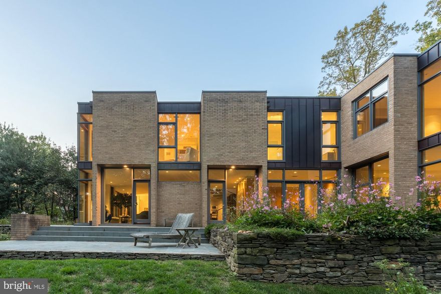 A modern home adjacent to national parkland, off of a private drive, located in one of the most desired sections of N. Arlington, and McLean. Originally designed by the coveted architect, Charles Goodman, then recently renovated with brilliant attention from the premier contemporary architect, Mark McInturff, FAIA., and impeccably executed by Added Dimensions Construction. Comfortably living on two wide levels with a floorplan enhanced by high ceilings and floor-to-ceiling glass, creating gorgeous exposures to the surrounding landscape that's lush with flowers and foliage. Upstairs the experience is breathtaking, as three-story volumes pull indirect natural light into the home, without disruption of privacy. The applied materials are timeless, elegant, and warm; portions of brick continue through the interior, while stained wood trim enhances the rich and natural aesthetic. Every space and all systems were improved, with all new bathrooms, a wonderful owner's suite, and a contemporary kitchen with premium finishes and appliances. This home offers the joys of mid-century modernism effortlessly, with a high-level contemporary renovation that is seamless, it is perfection.