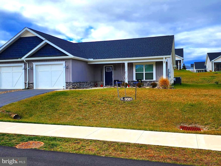 Built in 2021, The Maddy features 1,395 sq ft, 2 bedrooms, 2 baths, large kitchen island, quaint front porch, covered rear porch and a one car garage. Located just minutes from all your shopping needs in Falling Waters and I-81 for commuter's ease. This villa has been meticulously cared for and there was no expense spared in this home as the owners have many upgrades. The kitchen island was upgraded to a six-foot island with overhang for seating, island pendant lights, soft close cabinets & drawers by Timberlake and colored in Slate, appliances are upgraded to Slate Grey & an air fryer oven, fans in the primary bedroom & living room and the garage is painted and has shelving installed.