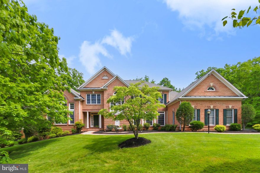 Welcome to 5448 Marlstone Lane in Fairfax, Virginia! Nestled in the desirable Popes Head Estates community, this exquisite 5.57 acre,  5 bedroom, 6.5 bath luxury home has it all—a stately brick façade with portico-style entrance, 3-car side-loading garage, multi-area deck and patios, hardwood floors, decorative moldings, coffered and tray ceilings, designer paint, and countless other upscale finishes and fine millwork. An abundance of windows bestow a light airy atmosphere and a perfect blend of personal and family oriented zones creates instant appeal.   
Fine craftsmanship begins in the grand two-story foyer with warm hardwood flooring that flows seamlessly into the elegant living room where a Palladian window streams natural light. Opposite the foyer, the banquet-sized dining room offers space for all occasions and is accented with decorative moldings and an elegant shimmering chandelier adding tailored distinction. The gourmet kitchen stirs the senses with gleaming granite countertops  and high-end appliances including a gas cooktop with suspended vented hood and French door refrigerator. Enjoy morning coffee at the center island’s bar seating, in the breakfast area, or step outside to the deck with descending stairs to natural stone patios sprinkled throughout this verdant and vibrant yard with expert landscaping—seamlessly blending indoor and outdoor dining and entertaining. Back inside, a spectacular sunroom with a curved wall of windows and a cozy family room  each provide the perfect spot for casual entertaining or simple relaxation, while a versatile main level bedroom suite/office space, laundry center/mudroom, second staircase, and powder room complement the main level.

Upstairs, the gracious primary suite boasts a sitting room, huge walk-in closet, and a luxurious en suite bath offering the finest in personal pampering with dual vanities, a sumptuous soaking tub, frameless ultra shower, separate water closet, and spa-toned tile flooring and surround. Down the hall, three additional bright and cheerful bedrooms each enjoy hardwood flooring, generous closet space, and a private bath. Continue down into the walkout lower level featuring an expansive recreation room with separate areas for games, media, and exercise. A bonus room combined with a full bath can serve as a learning center, guest or extended family suite,  as ample storage solutions complete the comfort and luxury of this unforgettable home. 
All this can be found in a peaceful setting that feels miles away from the hustle and bustle yet is so close to Route 123, the Fairfax County Parkway, Burke VRE, and Metro access. The picture of style and ease, your new home awaits. Welcome home!