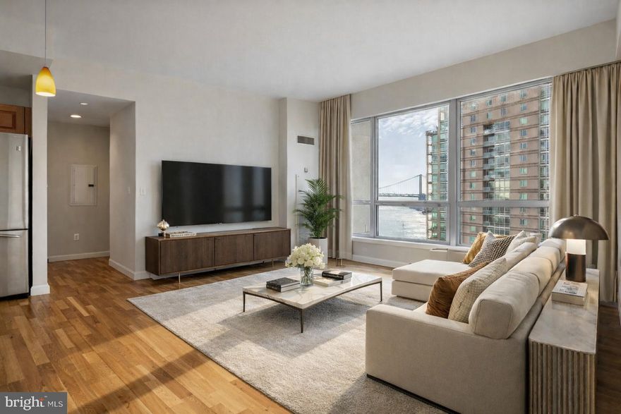 Perched on the desirable south side of the Regatta at Waterfront Square, Residence R704 offers a sophisticated one-bedroom plus true den layout defined by scale, light, and iconic views. Expansive window walls flood the residence with natural sunlight throughout the day while framing uninterrupted sightlines to the Benjamin Franklin Bridge and the shimmering Delaware River beyond.

The open-concept living and dining space is generous in both width and depth, anchored by warm hardwood flooring and clean architectural lines that create a refined yet inviting atmosphere. Oversized windows stretch across the living area, allowing light to pour in and offering a dramatic urban waterfront backdrop ideal for both everyday living and entertaining.

The kitchen is seamlessly integrated into the living space and features stainless steel appliances, granite countertops, tile backsplash, and abundant wood cabinetry—balancing functionality with timeless appeal. Thoughtfully placed lighting and open sightlines enhance the sense of flow throughout the home.

A fully enclosed true den—rarely found in one-bedroom layouts—offers remarkable flexibility. Bathed in natural light from floor-to-ceiling windows, this space is perfectly suited for a home office, guest room, nursery, or private retreat while maintaining privacy from the main living areas.

The bedroom is spacious and serene, comfortably accommodating a king-sized bed and additional furnishings while continuing the theme of abundant light and bridge views. The bathroom is well appointed with a granite-topped vanity, full Marble tile surround, and a jacuzzi soaking tub, delivering a spa-like escape at the end of the day. A dedicated laundry area with in-unit washer and dryer adds everyday convenience.

Residence R704 is located within Waterfront Square Condominium & Spa, Philadelphia’s premier gated waterfront enclave. Residents enjoy 24/7 guard-gated security, concierge services, and an unparalleled collection of resort-style amenities including an indoor pool and hot tub with river deck, state-of-the-art fitness center, sauna and steam rooms, massage suites, and elegant resident lounges. The three-level garage supports Philadelphia’s largest green roof, while 9.5 acres of meticulously landscaped riverfront grounds provide a tranquil and private setting. On-site management, advanced security systems, and weekday Global Limousine shuttle service to and from 30th Street Station ensure effortless city living.

Whether as a full-time residence or a refined city retreat, Residence R704 offers a rare combination of space, light, privacy, and iconic waterfront views—set within one of Philadelphia’s most prestigious residential communities. One parking license included!