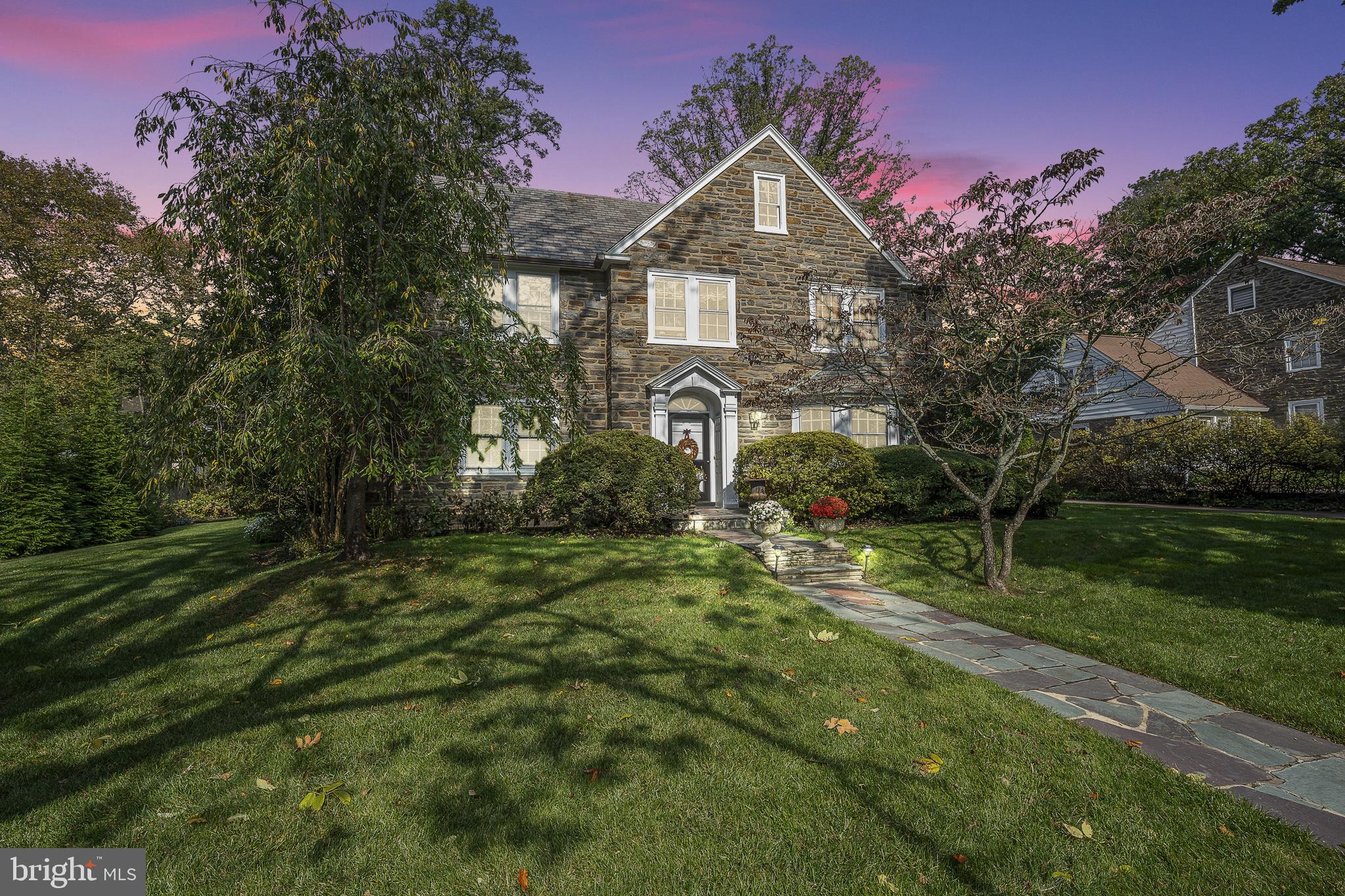 This classic center foyer stone colonial, constructed in 1933 and nestled in the sought-after Northside Haverford neighborhood, exudes enduring charm and elegance. Topped with a varied color slate roof, it carries an air of sophistication that stands strong over time.
As you step inside, you'll find handsome hand-pegged floors that flow seamlessly through the formal areas. The living room is generously bathed in natural light from three different directions, and French doors invite you to the peaceful blue stone terrace. A fireplace with a marble surround and wooden mantle provides a cozy centerpiece.
The dining room, with its chair rail and bay window, creates a welcoming space for large or intimate meals. The updated kitchen is a culinary haven, featuring a ceramic farm sink, Subzero refrigeration, and a practical 6-burner gas range with a griddle and. Added convenience comes in the form of a powder room, mudroom, and a discreetly tucked-away office space, all conveniently connected to the garage.
Climb the graceful staircase to the second level, where you'll find all five bedrooms. The primary suite is a personal retreat, boasting an ensuite bath, a fireplace, abundant southwestern sunlight, and three roomy reach-in closets. An adjacent bedroom, originally intended as a nursery but now an office, offers flexibility and potential expansion for the primary suite.
The third bedroom enjoys its own private bath with a tub/shower combination and a closet. Continue down the hall, passing a handy laundry shoot and double linen closet, and you'll discover an attractive second-level den featuring rich wood paneling, hardwood floors, a vaulted ceiling with overhead wood beams, and a stone-clad corner fireplace—a comfortable space for gatherings or work.
Completing this level are two more bedrooms and two additional baths, along with a convenient back staircase for ease of movement.
The lower level reveals a haven for recreation, with bead board paneling, built-in desks, another fireplace, and ample shelving. It also houses the home's laundry and storage facilities.
Outside, the property is fully fenced and boasts a charming front yard with a delightful tree swing, creating the perfect spot for outdoor enjoyment.
The location is unbeatable, with a short walk to the delightful shopping and dining options of Haverford Square. The nearby R5 train station provides easy access to the city. Nature enthusiasts will appreciate the bird sanctuary nearby, and the expanded neighborhood encourages exploration and a sense of community.
In essence, this classic colonial residence embodies timeless grace, modern living, and an unmatched sense of home—a gem of Northside Haverford.