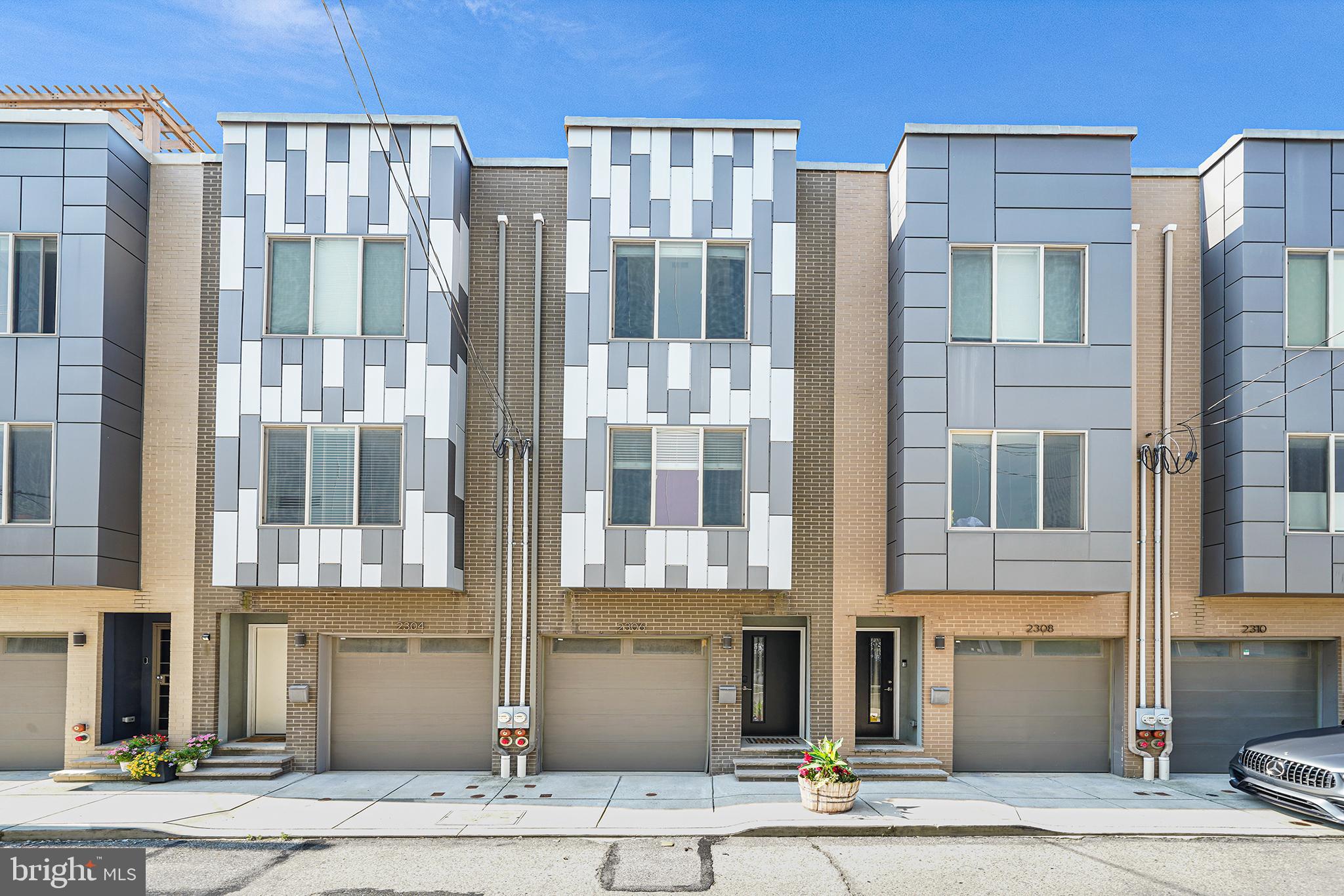 Welcome to 2306 Alter Street, a modern and well-kept four bedroom, four bathroom home with garage parking and over 2,000 square feet of smartly designed living space conveniently located in the Northern section of Point Breeze. When you enter this home, you are greeted by a recessed entryway complete with a coat closet. On this first level there is a full bathroom with a glass-door walk-in shower, a spacious bedroom with a row of closets and access to ground floor patio space. This bedroom offers great flexibility as it could easily function as a home office or an in-law suite. Upstairs, you’ll find an open concept kitchen, dining and living area absolutely flooded with natural light from an oversized front window. The kitchen is an ideal design with ample cabinet space, including a seamlessly built-in oversized pantry cabinet. The kitchen features a large island with cool gray cabinets and a white quartz countertop that not only provides a stunning design accent but also offers plenty of space for meal preparation and countertop dining. The kitchen has stainless steel appliances including a gas stove with hood, counter-depth refrigerator, dishwasher, built-in microwave and wine fridge. There is a sliding glass door off of the kitchen that provides access to a rear balcony that is perfect for summertime grilling. The living area itself easily fits large-scale furniture and is prewired for a wall mounted television. Dark toned solid hardwood floors flow throughout this home. The third floor of this home features the primary bedroom with an en suite bathroom, a guest bedroom and full guest bathroom with a tub. The primary bedroom has a full wall of closets, and the adjoining bathroom features an over-sized walk-in shower with neutral tile and custom glass shower door plus a floating double vanity for storage. A rarely found additional living space connected to a good-size roof deck is located on the fourth floor of this home. This roof deck adjacent living area has ample space making it the perfect alternative location for a primary bedroom. There is already a wet bar with sink and wine fridge installed in the space that could function as a coffee station should you opt to use this space as a bedroom. Downstairs, the finished basement of this home has refreshingly high ceilings, a full bathroom with another walk-in shower and a laundry room with extra space for storage. The finished area of the basement works as a second indoor living room space, a gym area or could even be utilized as an alternative location for yet another bedroom if so desired. This home combines functionality and thoughtful, versatile design that perfectly complement the urban lifestyle in a sought-after location less than a block over Washington Avenue in Northern Point Breeze and a short walk to neighborhood favorite businesses including Dock Street South, Breezy’s Deli, Small Oven Pastry Shop, Tuck & Barre Yoga and the new Aldi. Located in the Edwin M. Stanton Elementary School catchment.