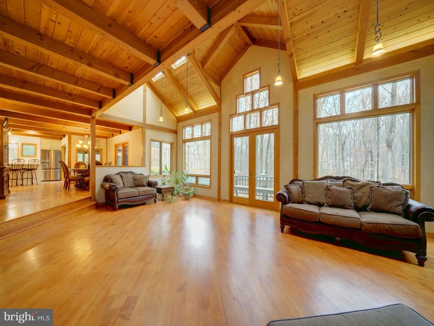 Spectacular custom built post and beam home built with a combination of beautiful woods including California Redwood and Western red cedar. Sitting atop a wooded 3+acre lot, the majestic mature trees have provided a quiet shelter of privacy for this spacious home. The green hillside and garden areas are surprisingly sunny, as the sun peers through the treetops. The front entryway has soothing ponds with fountains along the paved walkway to the front porch. The home has over 5500 sq ft inside with almost 5000 sq ft finished on 4 levels. Total of 6 bedrooms 3.5 baths, the open floor plan has soaring 2 story wood ceilings, skylights, and a full back wall of oversized windows with incredible views. Enjoy all 4 seasons peering out at the rolling hillside and watch wildlife in its natural setting. Birds including woodpeckers, owls, blue heron, hawks and plenty of deer and fox are frequent visitors. Cozy up to the fireplace in the main level great room or the woodstove in the lower level rec room, both providing ambiance and warmth to the home. The first floor offers a perfect home office wing complete with a private bathroom. The great room has built ins and plenty of natural light that flows through to the dining room and kitchen. Off the kitchen is a sunroom with windows on all sides. 1st floor mudroom with access to the 2 car garage from the main level or from the garret on the second level. The wood deck is the entire rear of the home with built in benches and pergola. The lower level is daylit with it's own exit that leads to an added driveway for convenience for guests during their stay. There is a guest suite with bedroom, full bath, kitchenette in addition to the huge rec room/gaming room combination. Plenty of storage in addition to the finished area. Upstairs the thoughtful design has included bedrooms with lofts, guest bath, access to the upper attic, bedroom level laundry room with washer/dryer and the primary suite. The primary en suite bath has many designer touches as expected in a custom built home including double vanity, soaking tub and separate tiled shower. The bedroom is spacious with an added sitting area. Adjoining the primary bath is access to the garret, space above the garage. The wood beam spans the entire length and has plenty of window light. There is a 2 person sauna, providing a relaxing escape in this hidden treasure space. There are 2 high energy efficient HVAC systems, newer hot water heater, all replaced within the past year. There is a  whole house generator in case of emergency and gutter helmets. The home sits back off the main road with a shared driveway that ends where the private circular driveway and extended driveway meet. Plenty of room for parking. Clarksville has a wonderful town center with large community center with shopping, dining and recreational features. Downtown Columbia and Historic Ellicott City are only a short drive away. Convenient to major Routes 32, I70 and Rt 29, perfect commuter community with easy drive to Baltimore or Washington suburbs and the BWI business district. John Hopkins Howard County Medical Center, JHUAPL and Ft Meade/NSA are just a few of the employment centers close by. Howard County parks, recreation and schools are all highly desired. This home is a wonderful choice, offering a unique design, serene setting yet so convenient.  Call your agent to set up a private tour.