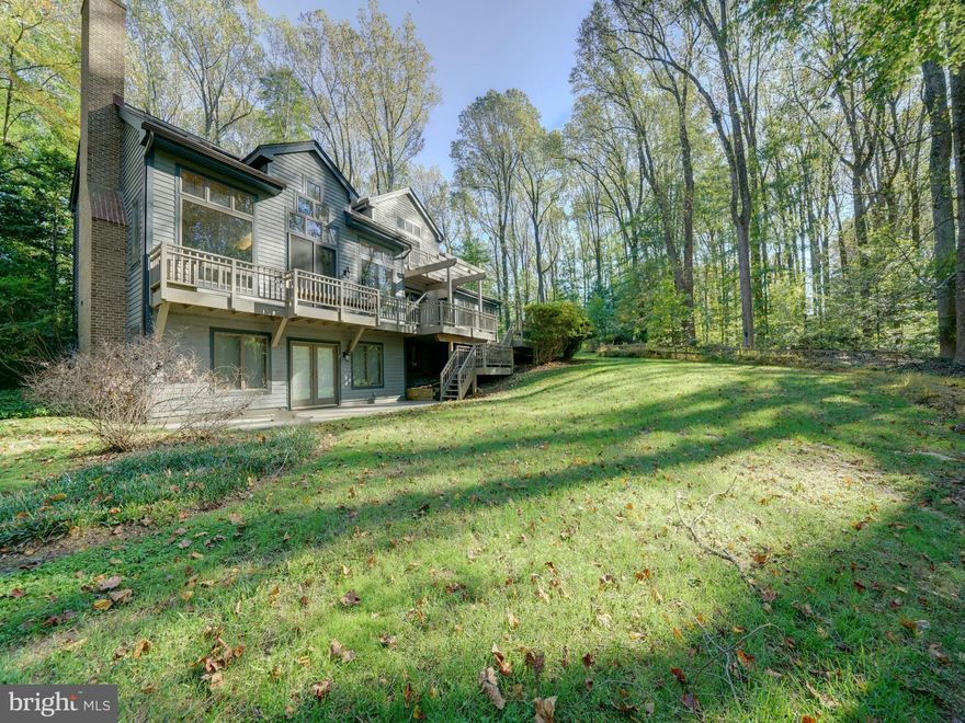 Spectacular custom built post and beam home built with a combination of beautiful woods including California Redwood and Western red cedar. Sitting atop a wooded 3+acre lot, the majestic mature trees have provided a quiet shelter of privacy for this spacious home. The green hillside and garden areas are surprisingly sunny, as the sun peers through the treetops. The front entryway has soothing ponds with fountains along the paved walkway to the front porch. The home has over 5500 sq ft inside with almost 5000 sq ft finished on 4 levels. Total of 5 bedrooms 3.5 baths, the open floor plan has soaring 2 story wood ceilings, skylights, and a full back wall of oversized windows with incredible views. Enjoy all 4 seasons peering out at the rolling hillside and watch wildlife in its natural setting. Birds including woodpeckers, owls, blue heron, hawks and plenty of deer and fox are frequent visitors. Cozy up to the fireplace in the main level great room or the woodstove in the lower level rec room, both providing ambiance and warmth to the home. The first floor offers a perfect home office wing complete with a private bathroom. The great room has built ins and plenty of natural light that flows through to the dining room and kitchen. Off the kitchen is a sunroom with windows on all sides. 1st floor mudroom with access to the 2 car garage from the main level or from the garret on the second level. The wood deck is the entire rear of the home with built in benches and pergola. The lower level is daylit with it's own exit that leads to an added driveway for convenience for guests during their stay. There is a guest suite with bedroom, full bath, kitchenette in addition to the huge rec room/gaming room combination. Plenty of storage in addition to the finished area. Upstairs the thoughtful design has included bedrooms with lofts, guest bath, access to the upper attic, bedroom level laundry room with washer/dryer and the primary suite. The primary en suite bath has many designer touches as expected in a custom built home including double vanity, soaking tub and separate tiled shower. The bedroom is spacious with an added sitting area. Adjoining the primary bath is access to the garret, space above the garage. The wood beam spans the entire length and has plenty of window light. There is a 2 person sauna, providing a relaxing escape in this hidden treasure space. There are 2 high energy efficient HVAC systems, newer hot water heater, all replaced within the past year. There is a  whole house generator in case of emergency and gutter helmets. The home sits back off the main road with a shared driveway that ends where the private circular driveway and extended driveway meet. Plenty of room for parking. Clarksville has a wonderful town center with large community center with shopping, dining and recreational features. Downtown Columbia and Historic Ellicott City are only a short drive away. Convenient to major Routes 32, I70 and Rt 29, perfect commuter community with easy drive to Baltimore or Washington suburbs and the BWI business district. John Hopkins Howard County Medical Center, JHUAPL and Ft Meade/NSA are just a few of the employment centers close by. Howard County parks, recreation and schools are all highly desired. This home is a wonderful choice, offering a unique design, serene setting yet so convenient.  Call your agent to set up a private tour.