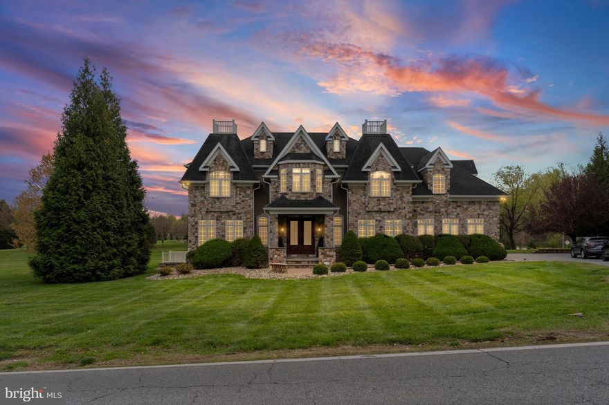 Commanding in presence and impeccable in finish, this distinguished Colonial estate rises with quiet authority on over two acres of manicured, private grounds. Completed in 2008 to an uncompromising standard, 2301 Old Bosley Road offers more than 5,000 square feet of masterfully appointed living — a residence that rewards at every turn.

A grand covered front porch announces the arrival experience before you ever reach the threshold. Soaring double entry doors open to a statement foyer where a bifurcated staircase sweeps to the upper level beneath a magnificent chandelier, its warm light falling across gleaming hardwood floors. Flanking this entry hall with perfect symmetry, a formal dining room and a refined formal living room each present elevated tray ceilings — spaces conceived for gracious entertaining and quiet reflection alike. A discreet powder room completes this level's welcome suite.

The heart of the home is a generous family room anchored by a gas fireplace — an intimate gathering space that opens with ease through double patio doors onto a sweeping deck overlooking the estate grounds, where two acres of immaculate lawn invite outdoor living of the highest order.

Adjoining the family room, a chef's gourmet kitchen of rare distinction awaits. Custom cabinetry rises to impressive heights, crowned by hand-selected granite countertops and artisan tile backsplash. A professional-grade range with grill and dual ovens anchors the culinary space, thoughtfully equipped with an overhead pot filler for seamless, unhurried cooking. A multi-zone sink layout and top-of-class stainless appliances — including a double-department dishwasher — reflect the high-efficiency design philosophy throughout. A fully appointed butler's pantry, discreetly positioned off the family room, provides a second kitchen and dedicated laundry connections, ensuring every domestic requirement is met with elegance and privacy.

Descending to the lower level reveals a fully finished basement spanning the home's entire footprint — a remarkable amenity space warmed by a second gas fireplace. Here, a dedicated wine cellar awaits the discerning collector, accompanied by a full bathroom and well-organized mechanical facilities. The estate is served by a private well and septic system, offering true independence and long-term value.

Upstairs, the owner's suite is a sanctuary of its own measure. The spa-calibrated en-suite bath presents a deep soaking tub, a walk-in shower with dual rainfall heads, a heated towel warmer, and dual vanities — an indulgence in everyday ritual. A private balcony extends the suite's reach, offering a serene overlook of the home's grand interior below. Three additional bedrooms are generously proportioned, each with walk-in closet storage; two share a thoughtfully designed jack-and-jill bath, while the fourth enjoys its own private en-suite. Architectural lighting in each bedroom adapts to the owner's mood with customizable settings, and oversized windows flood every room with exceptional natural light. Adding a final note of practical luxury, a dedicated laundry room is conveniently positioned on this upper level — keeping household routines entirely separate from living spaces and effortlessly close to every bedroom.

Among the estate's many amenities: a whole-home central vacuum system, eight ceiling fans, a built-in whole-home generator ensuring uninterrupted comfort, and a three-car garage complemented by a five-car asphalt motor court. A utility shed provides additional storage. This is a home without concession — a rare Colonial estate offering the space, the finishes, and the serenity that true luxury demands.