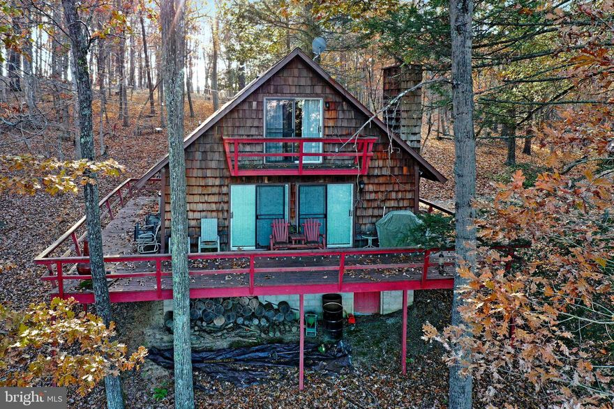 Cacapon River Access!! Situated on 5.34 Acres in gated communty, this well maintained cabin is the perfect get away from the business of the city. Open Living Room/Dining/Kitchen with stone woodburning fireplace.   Dining and Living room lead to a spacious wraparound deck.   1 bedroom and 1 bath on the main level, 2 bedroom and half bath on upper level.   Balcony off one of the bedrooms.  Beautiful mountain views.   Located in the locked gate community of River Ridge with access to a  pristine community park with stone BBQ's, picninc tables, storage racks for kayaks/canoes, access to the Cacapon River for floating in a canoe, kayak or tube and bathroom facility on site.