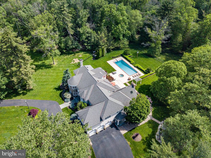 Welcome to 1049 McKean Road, the 2nd largest residence in Horsham Twp - timeless elegance meets modern luxury in this extraordinary custom-built estate nestled on 14.62 whimsical, park-like acres - only  2 acres are grassy and require maintenance, with the remainder being wooded. A long private drive and charming wooden bridge set the tone for the serene lifestyle that awaits. Framed by meticulously manicured landscaping, this 12,000+ sq. ft. Manor Home offers 5/6 expansive bedrooms—each with its own Full Bath and Walk-In Closet—designed for both grand entertaining & private comfort. Upon arrival, the circular driveway invites you into a breathtaking Two-Story Foyer adorned with limestone flooring, a striking turned oak staircase with carpet runner, and a sparkling hanging crystal chandelier, all beneath a second-floor Balcony. To the left, the turret-style Living Room enchants with oversized windows, luxe carpeting, and recessed lighting, while the Formal Dining Room on the right impresses with hardwood floors, another dazzling chandelier, and elegant trim work. The gourmet Kitchen is a culinary dream, outfitted w/ rich cherry cabinetry, granite countertops, GE Monogram stainless steel appliances, a center island with seating for six, and a Walk-In Butler’s Pantry—all connected to a vaulted Great Room featuring 27’ ceilings, a custom mahogany entertainment center, floor-to-ceiling stone fireplace, surround sound, and a second oak staircase to the upper level. Additional main-level highlights include a richly appointed Home Office and a light-filled Conservatory w/ a gas fireplace and stunning quarter-sawn oak hardwood floors accented with a walnut medallion inlay. Upstairs, the turret-style Primary Bedroom Suite is a luxurious private retreat. Vaulted ceilings are adorned with exquisite hand-painted artwork, extending into the cozy Sitting Room w/ its own gas fireplace. Dual Walk-In Closets provide abundant storage, while the lavish Primary Bath features marble floors, dual vanities, walk-in shower stall, and his-and-her water closets, and a deep jacuzzi tub—every element designed for indulgent relaxation. A spacious upper-level Laundry Room includes two washers, two dryers, a utility sink, and a separate space for folding, hanging, and ironing. The uppermost level offers a Finished Loft/Recreation Room with tranquil views of the Backyard Oasis. The fully finished Walk-Out Basement provides an additional layer of luxury and comfort, featuring a large Recreation Room, Guest Bedroom, Exercise Room, Full Bath with steam and walk-in shower, and a dedicated Theater Room. Two separate staircases ensure seamless access to the Main Level, while recessed LED lighting enhances the ambiance throughout. Step outside to your own private resort: a fenced Backyard Oasis complete with a resurfaced custom concrete Patio, In-Ground Pool with updated tiles, coping, and a motorized retractable cover, a rejuvenating Spa, and a Pool Shed. Nearby, a refinished Koi Pond with flagstone Seating Area invites moments of serenity, while professionally installed paver walkways connect the home’s front and side entrances. Additional features include a 7-zone high-efficiency HVAC system powered by a condensing natural gas boiler & furnace for year-round comfort, an Attached Heated 3-car Garage with epoxy floors, storage closets, and guest-accessible Powder Room, plus a Detached 3-car Garage with updated roof, concrete flooring, and separate electric service. A whole-home natural gas Generac generator, irrigation system, exterior LED accent lighting, 400-amp electrical service, newer water heater, and fresh interior paint and carpeting throughout further enhance the value and sophistication of this remarkable estate. Experience unparalleled privacy, craftsmanship, and luxury living at 1049 McKean Road—an extraordinary retreat that truly has it all. Nowhere else will you find a home of this size on this many acres in Horsham Township!