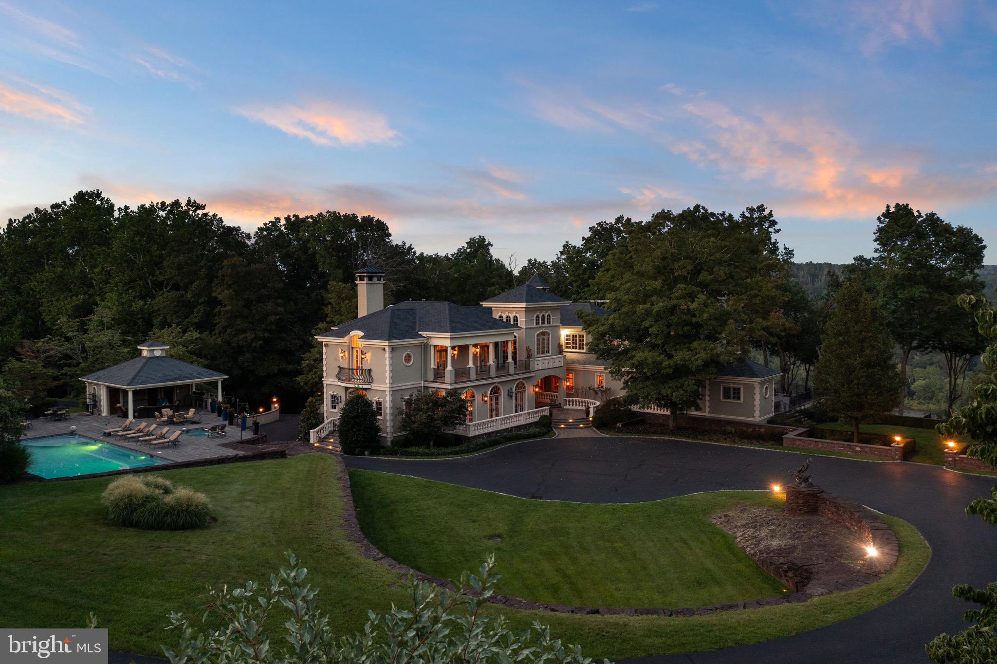 COMING TO AUCTION Monday April 29th, 11 am ON SITE!! Come and take a tour this week OR over the weekend!!! This Saturday and Sunday there is an OPEN HOUSE, 10 am to 6 PM, by appt. Nestled in the heart of Bucks County, Pennsylvania, this exquisite Italianite estate unfolds over 11 acres of meticulously manicured land, offering a sanctuary of seclusion and expansiveness that captivates at first sight. The approach is graced with a heated driveway at the impressive custom iron gates ensuring unimpeded access regardless of the weather, a nod to the thoughtful engineering that defines the property, setting the tone for an experience of unmatched exclusivity and security, underscored by the inclusion of a state-of-the-art SAFE ROOM and 32 exterior cameras. Its crowning glory is the breathtaking vista over the majestic Delaware River, presenting a sweeping panorama that enchants and soothes in equal measure. Accompanied by a generously proportioned two bedroom guest house, this estate effortlessly accommodates esteemed visitors or serves as a luxurious rental retreat, enhancing its allure. The presence of a sumptuous heated pool, separate hot tub, and pavilion with full bath, dressing room, outdoor kitchen (and more) adds a layer of opulence, offering a serene escape during the warmer months. For those with an affinity for automotive excellence, the provision of multiple heated garages with solid mahogany doors, tiled floors, one with an integrated lift, full compressor systems, & hot and cold running water . This provision furnishes an expanse amply capacious to house and maintain an impressive collection of vehicles, catering to the desires of avid car connoisseurs. Spanning over approx 15,000 square feet, this architectural marvel marries the timeless elegance of Italian design with the pinnacle of modern luxury. A majestic 50 year slate roof with a durable 6-inch pitch along with the massive amount of rocks quarried from the property, set the tone for a true masterpiece. Inside, the great room, a focal point of grandeur and sophistication, features dual-layered three-quarter-inch thick plywood floors, topped with grain-matched Brazilian cherry of unmatched length, a rarity in the United States today. This exquisite flooring is complemented by natural cherry baseboards and trim, finished with tongue oil for a rich, authentic lustre without the use of polyurethane. The bar area is adorned with book-matched green onyx slabs, while a limestone Rumford fireplace provides a warm, inviting ambiance. The luxury extends throughout, with over 5,000 square feet of Brazilian cherry flooring on the first floor alone, leading up to a staircase of hand-hammered, clear-coated Brazilian cherry and hand hammered ironwork, showcasing exquisite craftsmanship without a nail in sight. On the second floor is the Owner's suite complete with home office along with several other guest rooms. The office and primary suite elevate the concept of luxury, featuring Brazilian cherry and Ashwood ceilings respectively. The entrance of the primary suite includes an 18th-century buffet transformed into a coffee bar with subzero freezer/refrigerator drawers and sink with filtered water, a primary bath with heated floors, towel warmer drawers, backlit onyx, soaking tub, gas fireplace, and dual-head steam shower, and two expansive walk-in closets. The property’s outdoor spaces are equally distinguished, with precast stone patios, solid cast aluminum railings, and a comprehensive security system, ensuring elegance and peace of mind.Outdoors, precast stone patios with lilac stone inlays, solid powder coated cast aluminum railings. The property also features a water treatment system and a 125 kW generator. This Bucks County estate is not just a home but a legacy, offering a living experience crafted with precision and care