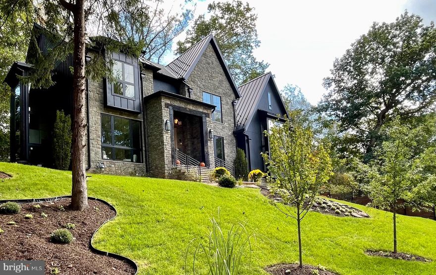 A relaxed luxury where timeless elegance blends effortlessly with refined comfort. A true expression of modern sophistication. From serene retreats in Washington, D.C. to countryside escapes reimagined in an urban setting, every detail of this home tells a story in the heart of Chesterbrook Woods, one of McLean’s premier neighborhoods.

The exterior captivates with meticulous craftsmanship. Twelve-foot beams at the front entrance complement intricate stonework, while a grand Canadian maple Andersen door exudes striking presence. French gas lanterns paired with RH light fixtures add refined charm. A metal roof blends seamlessly with premium architectural shingles, and the façade combines stone with Shou Sugi Ban siding, accented by thoughtful landscaping that completes this cohesive architectural statement.

At the heart of the home is a breathtaking thirty-foot-high lounge crowned with sixteen-foot windows, featuring a reclaimed roof rafter from 1847, salvaged from the last cotton mill of Virginia, that invites cascades of natural light throughout the day. The room, wrapped in century-old rugged heart pine and dark textured brick, carries a stillness that resonates deeply. Exposed roof rafters meticulously wrapped in birch wood add organic warmth to the soaring volume and create a space where serene grandeur meets quiet storytelling. Suspended above, the Arcachon Round brass chandelier anchors the room with rhythmic grace. Below, a custom-built fireplace framed by built-in bookshelves offers both intimacy and presence.

The kitchen is an artful composition of form, light, and texture. A ten-foot brass-textured waterfall countertop exudes understated charm, while sun-filled windows invite the day’s shifting moods. The Fulcrum Pendant, with its hand-blown glass and brass, hovers sculpturally, casting a gentle glow. Limestone walls evoke the Tuscan countryside’s earthy timelessness. Chevron white oak floors, soft-toned cabinetry, and polished brass hardware from the Camden Collection, inspired by mid-century French and Italian design, blend quiet confidence with craftsmanship. Reclaimed beams paired with structural I-beams create a dialogue between history and modernity, making the kitchen a celebration of refined restraint and comfort.

A slatted ceiling designed and constructed onsite guides you toward the dining area with a rhythm that feels intentional and fluid. There, a Tiered Rectangular Chandelier from the Marignan Collection, composed of more than one thousand crystal elements, takes center stage. Its interlocking formations float effortlessly, casting a shimmering cascade of light that fills the space with quiet drama.

The Thaddeus Powder Room collection, inspired by the surreal artistry of Salvador Dalí and Diego Giacometti, features hand-forged metals, a bespoke custom sink, and refined fixtures that intertwine with effortless sophistication, resonating with the home’s cohesive aesthetic. (This offers just a glimpse of the main level, with even more to explore throughout the home.)

At its core, every house should tell a story, with each space unfolding as a meaningful chapter that endures over time, crafting environments that awaken reflection and wonder, where elegance and beauty invite you to slow down, breathe deeply, and embrace the true essence of feeling at home.