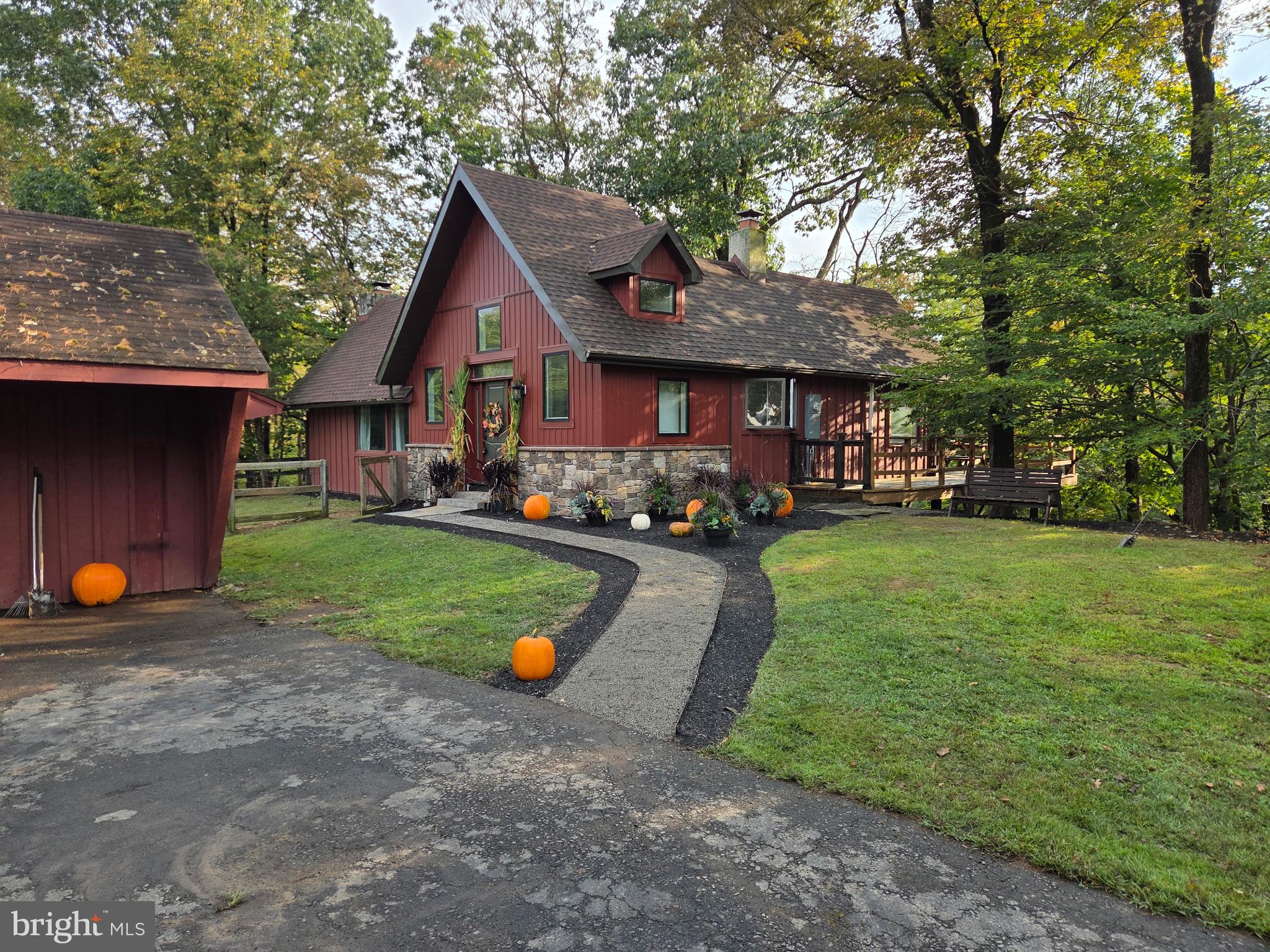 Tucked away at the end of a private drive, this custom-built rustic cottage sits on 2.26 wooded acres overlooking the Neshaminy Creek. A wraparound, two-level deck offers stunning views of the water and surrounding trees, creating the perfect private retreat. Step inside to a tiled foyer that opens to the impressive great room, featuring a 17’ vaulted, beamed ceiling, a full stone fireplace, gleaming hardwood floors, and walls of windows that fill the space with natural light. The kitchen offers designer cabinetry, stainless steel appliances, a double refrigerator, built-in microwave, and access to the rear deck for easy indoor-outdoor living. The spacious bedroom is a true retreat with a vaulted ceiling, exposed beams, stone wall fireplace, walk-in closet, and oversized windows. The updated bathroom includes a glass-enclosed double shower, counter-height vanity, tiled floor. Mud room with laundry area and powder room. A cozy loft overlooks the great room, perfect for an office or reading nook. Outdoors, enjoy the large two-level wraparound deck where you can relax and take in the sights and sounds of nature. Additional features include a detached oversized two-car garage (23' x 19'), plus a second large garage-style storage shed ideal for equipment. Surrounded by trees and backing to township parkland across the creek, this home provides a peaceful, secluded setting while still being just minutes from major roads, shopping, dining, and conveniences. A rare opportunity for a private retreat with easy access to everything—schedule your showing today!