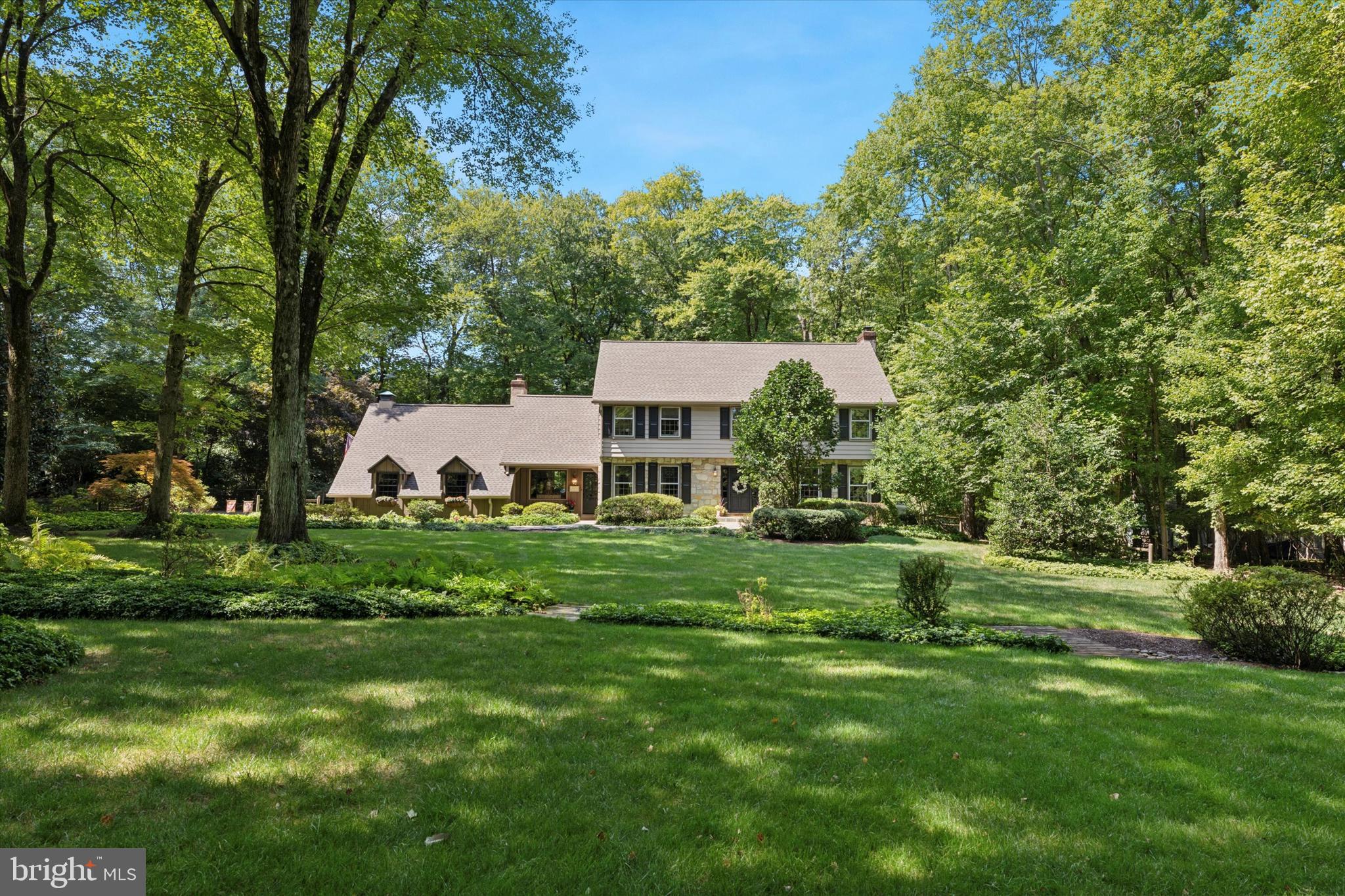 Welcome to Your Serene Retreat...
Nestled at the end of a private lane, this custom Sweeney-built home from the 1960s, with its distinctive stone front, offers a tranquil escape on 1.79 lush, wooded acres. From the moment you step onto the Mercer tile floor of the inviting foyer, you’ll be captivated by the custom molding, rich hardwood floors, and built-in bookcases that define this unique residence. Every window frames breathtaking views of the surrounding nature, where in spring, you might spot fawns playing among the trees and, in winter, the graceful red fox darting through the snow. Your journey begins in the expansive living room, where a propane gas fireplace creates a cozy focal point, complemented by four large windows and French glass doors that open to a covered porch and bluestone patio accented by stone walls, custom fire pit and built-in gas grill all overlooking an incredibly private and peaceful, serene backyard. This outdoor space is an entertainer’s dream! The newly renovated kitchen is a chef’s delight, boasting custom inset cabinetry, a walnut island, soapstone countertops, and a subway tile backsplash. Equipped with Thermador appliances, radiant heated floors and a pantry, this kitchen also includes a charming bay window that frames views of your personal paradise. The adjacent family room, with its newly added built-in bookcases, brick wood-burning fireplace, and beamed ceiling, is one step down from the kitchen. Radiant floor heating and two picture windows enhance the room’s warmth and charm. A door leads to a small patio that connects to the oversized two-car garage, making errands a breeze. The first floor also features a formal dining room, a built-in bar area with custom cabinetry, a wine fridge, and a convenient powder room. Upstairs, the master suite is a haven of comfort and luxury, showcasing hardwood floors, a spacious walk-in closet, and a Carrera marble bath with a full glass shower, custom vanity and radiant floor heating. The suite also includes a bonus room currently used as a home office. The hall bath has been thoughtfully renovated with custom cabinets, Carrera marble shower/tub, double sinks, radiant-heated floors, and a built-in linen closet. Three additional generously sized bedrooms, each with ample closet space and picturesque views, complete the second floor. Recent updates include a brand-new roof (2023) with a 50-year warranty, new gutters, high-efficiency heat pump systems, hot water radiant heat, and an emergency generator hook-up. For those seeking a peaceful retreat with stunning landscaping, miles of walking trails, and proximity to the highly-ranked Wissahickon schools, Whole Foods shopping center, and SEPTA train to Center City, your dream home awaits.