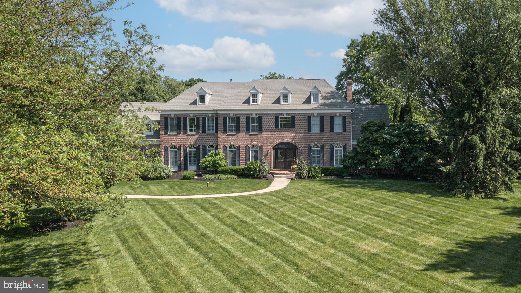 Nestled in the sought-after Wrightstown Hunt community, this charming brick colonial sits on a beautiful 4-acre lot, surrounded by mature trees and lush landscapes. As you approach the entrance, you'll be greeted by a welcoming double door, transom windows, and intricate dentil molding. Upon entering, you'll be impressed by the open, two-story foyer with a graceful, curved staircase, decorative moldings, and rich hardwood floors. The home offers generously sized rooms with stylish upgrades and detailed designs that create a warm and inviting atmosphere. The newly renovated, gourmet kitchen is the heart of this home, featuring custom neutral-toned cabinetry, a mix of quartz and granite countertops, a spacious island with seating for five, and high-end appliances. The kitchen seamlessly flows into the family room, which boasts a cozy gas fireplace and a two-story dining area. The sunroom, with its double-paned French doors and walls of windows, offers a delightful space for enjoying meals or hosting gatherings while overlooking the expansive yard. The family room and billiards room provide ample space for entertainment, and the conservatory, with its custom built-in bar area, gas fireplace, and vaulted ceilings, offers stunning views of the private pool area. The primary bedroom suite is a true retreat, featuring a tray ceiling, a sitting room converted into a walk-in closet, a balcony overlooking the yard, a dressing area with additional walk-in closets, and a newly renovated luxurious bath. Three additional spacious bedrooms and a Bonus Room (5th bed potential) complete the upper level. The finished lower level is equally impressive, with a theater area, gaming space, golf simulator, exercise room, flex room, and full bath, providing endless opportunities for entertainment and relaxation. Enjoy outdoor living with an in-ground, heated swimming pool and private outdoor living areas. The home also features thoughtful touches like plantation shutters and custom light fixtures throughout. Located in the award-winning Council Rock North School District, with shopping and dining options nearby in Newtown and New Hope, and convenient commuter routes, this enchanting home offers the perfect blend of luxurious living and accessibility. Schedule your private tour today and discover the epitome of refined living.