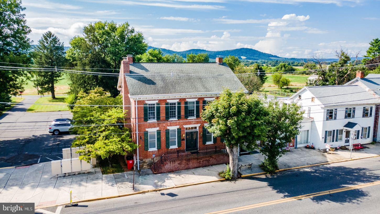 Spectacular pre-civil war home circa 1850, complete with the official plaque on the front of the home! This home has a vast amount of history within its walls starting with the builder being the one of the Musselman brothers who are also known for their applesauce. This property is zoned both residential and commercial, with 5,000 + square feet, making the possibilities endless. Enter the home and step back into an era gone by; full of tons of character and charm, but loaded with all of the updates and modern day conveniences you would want. The stunning hardwood floors in the foyer carry throughout the 1st floor, and the open staircase and chandelier will warm your heart. The living room on the left has a wood burning fireplace and leads you to the stunning, updated kitchen. The kitchen has exposed beams, quartz counter tops, a big island with slide in gas range, pot holder, and a built in desk and big pantry cabinet. The formal dining room will come in handy for the upcoming holiday parties. 1st floor bedroom features Indian shutters on the windows which completely darken the room, and a full bath makes this great as a primary or guest area. Upstairs, there are 3 bedrooms and 2 full baths. There is another bedroom above the summer kitchen! The garage is accessible from the main house and the 2nd floor is currently being used a rec room and this is also where the 4th full bathroom is located. This home also features upper and lower porches in the back of the home. The yard is beautifully landscaped and has planters boxes already set up. This one of kind home is one that you do not want to miss!