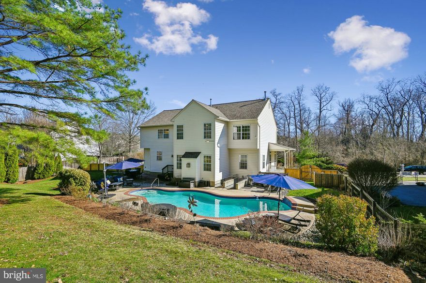 Beautiful and convenient, this Cambria home awaits you in Davidsonville.  The residence features five bedrooms -- a primary suite, one ensuite and three sharing a newly updated hallway bathroom. The primary suite has a stunningly  renovated full bathroom with double sinks, a soaking tub, shower, and private water closet. The bedroom is highlighted with  two walk-in closets and a windowed alcove sitting area. Formal living and dining rooms are situated on either side of the two-story foyer. The kitchen has all the major stainless kitchen appliances , a huge granite topped center island plus an abundance of cabinets and pantry.  The "full table" eating area  opens to the spacious family room, featuring a gas fireplace.  A sunlit office is located on the main level. The lower level provides a retreat with an additional guest room/  office,  second family room,  full bathroom, and a workroom that includes added storage possibilities. The property boasts an inground swimming pool, expertly hardscaped for relaxation and entertaining.
The landscaped grounds include a water feature within the fenced rear yard.  Improvements: Roof- 2021,
Dishwasher, Washer, Dryer - 2021, Swimming Pool Pump and Heater - 2021, Gutters- 2024,  Oven and Microwave- 2026