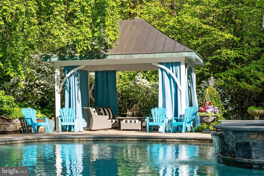 MAKE SURE YOU VIEW ALL THE PHOTOS OF 10205 Cedar Pond Drive is where the Fairy Tale Begins.  With over 7400 Sq. Ft. of Living Space this  HIDDEN OASIS IN ONE OF THE MOST SOUGHT-AFTER AREAS OF VIENNA.  Magnificently sited on 1.23 acres backing to 15 acres of woods, this exceptional estate offers unmatched privacy and character while remaining just minutes from McLean, Tysons, and Reston Town Center.
The approach begins with a gentle hilltop location and meticulously landscaped grounds framed by mature trees, setting the stage for the romantic architecture and elegant interiors. At the heart of the home, a stunning custom kitchen by Apex Homes features custom Neff cabinetry, professional-grade Wolf and Sub-Zero appliances, and an expansive design ideal for both everyday living and entertaining. The adjoining formal dining room is highlighted by a dramatic plaster groin-vaulted ceiling and walls of windows that capture serene views of the landscaped grounds and pool beyond. A sun-filled garden room opens directly to the rear terrace, blending indoor and outdoor living. The spacious main-level family room adjoins a paneled study providing the option of a first-floor primary suite.
The rear garden is a resort-like destination, featuring stone terraces, formal gardens, fountains, and mature trees—all anchored by a resort-style swimming pool, spa, fire pit, and two custom gazebos.
Upstairs, the primary suite offers a fireplace, an extraordinary custom dressing room with handcrafted burled walnut and mahogany cabinetry, and a spa-inspired bath designed for relaxation—two additional bedrooms on this level feature cathedral ceilings and abundant windows overlooking the gardens.  The lower level provides remarkable flexibility for guest accommodations, fitness, media, or lounge space.
Every room reflects a commitment to quality and craftsmanship, with timeless design, abundant natural light, and a seamless blend of European character and luxury. This is more than a home—it’s a lifestyle.
