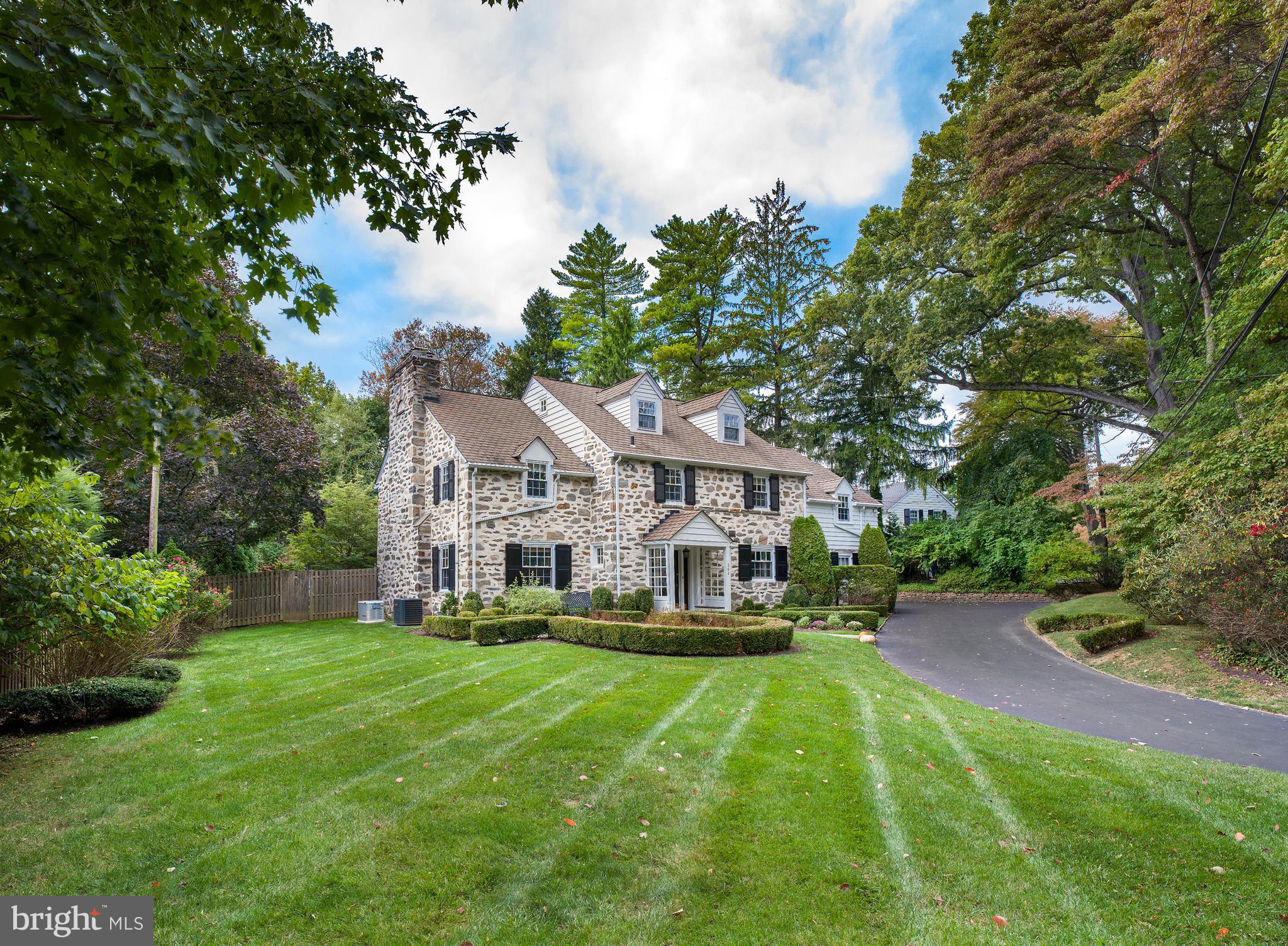 Majestic 5 bedroom, 3.2 bathroom stone colonial on a pristine half acre of property, located at the gateway to Montgomery School Lane and stones throw from the Lower School of Freinds Central. This home has a huge private fenced-in yard, lovely landscaped patios and gardens, and built-in 2-car garage! This exquisitely restored and updated home blends old world charm with modern amenities, affording living comfort for the family and a perfect backdrop for entertaining. The gracious entry foyer welcoming you inside boasts tasteful millwork and rich hardwood floors that flow throughout the home. The large formal living room, handsome wood-paneled library with a corner gas-burning fireplace, and wainscoted dining room set an elegant yet comfortable tone when hosting guests. Gather around the big island as the cook prepares meals in the stunning gourmet kitchen, featuring granite countertops, wood cabinetry, a built-in refrigerator and dishwasher, double wall ovens, 6-burner gas cooktop with grill, wet bar with sink and wine fridge. Enjoy coffee and casual fare in the sunny breakfast room brightened by a picture window overlooking the tranquil yard, with a Dutch door accessing the patio. Also open to the kitchen is a spacious family room offering a gas fireplace, built-in bookcases, and double French doors to the patio and rear grounds for easy indoor-outdoor parties. Ascend the main or rear staircase to the hardwood 2nd level presenting the master suite, 4 family/guest bedrooms with connecting Jack & Jill baths, and a laundry room. The fabulous master suite entered through a private hallway boasts a vaulted bedroom with gas fireplace, wainscoting, sitting area, and sliding doors to a Juliet balcony. His & her walk-in closets, and a fabulous bath with dual vanities, jetted spa tub and oversized shower complete the luxury experience. The finished 3rd level/walk-up attic serves as a great bonus room for multiple purposes. On the lower level is additional living space with a family/rec room, fireplace, half bath, wine room, workshop, unfinished space and abundant storage. Situated in a prime location near shopping, schools, restaurants, and Center City.