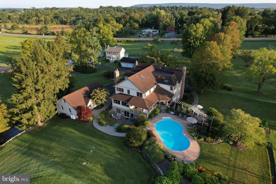 Nestled on an expansive 11-acre estate in the Colyer Lake community, this stunning property features a grand 8,000-square-foot main residence complemented by a 1,800-square-foot caretaker's home. The grounds include a newer barn with accommodations for four horses, four fenced-in pastures, a stocked trout stream, a beautiful pond that is filled with bass, catfish and other species (a great ice skating rink in the winter!), a mini barn and storage sheds. 

The main house dates back to the late 1800's, with several additions and updates making it a blend of historic charm and contemporary luxury.  When you step on the property you'll notice  the owners have poured a lot of care into the maintenance of the home and were thoughtful with the updates. The original wood plank floors shine throughout the original half of the home and reclaimed wood harvested from the attic of the caretaker's home completes the flooring throughout the addition. The heart of the home, a chef's kitchen, boasts state of the art appliances, custom cherry cabinetry, a large center island and a walk-in pantry. Adjacent is the elegant dining room, ideal for hosting intimate dinners. Also on the first floor is a formal sitting room, a family room with a wood burning fireplace and French doors, and a living room with breathtaking views of the pond, mountains and pastures. 

The owner's suite is bathed in natural light and features tray ceilings, a spacious bathroom with custom tile work, a large walk-in closet, and an attached private office, providing both comfort and convenience in one luxurious space.  There is an additional ensuite on the second floor with a cathedral ceiling, ample closet space, and a gas burning fireplace. Two more large bedrooms, an additional full bathroom and laundry room, both with heated tile floors, complete the second floor. 

There is a finished attic with space for guests, or hobbies. The finished basement includes a recreational room, an additional living space, a kitchenette, a full bathroom and full walkout access to the beautiful in-ground pool. The pool is surrounded by professional landscaping and hardscaping making it the perfect spot for summer relaxation.

The estate also features a heated, three-car, detached garage with adjoining workshop and loft storage along with an additional detached, two-car garage with workshop to complement the caretaker home. Adding to its charm, the estate holds a rich history, highlighted by a historic bridge original of SR 322 dating back to 1904. This property is a rare gem, offering a unique blend of luxury, nature and history.

Guest House
Main level  Living room    17x16
Main level Dining room   12x15
Main level  Kitchen    12x20
Main level  Laundry/mudroom  8x15
Upper 1 Office    11x7
Upper 1 Bedroom 1  14x12
Upper 1 Bedroom 2  16x9
Upper 1 Bedroom 3   15x12
Upper 1 Bathroom    16x9

20-006-,096-,0000- 7.06 acres with main house, garage and barn
20-005-,064-,0000- 1 acres with Caretaker house, garage and shed
20-006-,096B,0000- 1.03 acre lot with shed
20-005-,061C,0000- 1.4 acre lot
*Main home is not located in a flood zone, but some parts of the property are.*