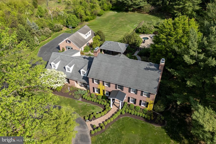 Nestled on 2.23 pristine acres in one of SAUCON VALLEY'S MOST COVETED LOCATIONS, this stately BRICK COLONIAL seamlessly blends CLASSIC ELEGANCE with MODERN UPDATES. Thoughtfully reimagined, the home features a GOURMET KITCHEN with quartz countertops, custom cabinetry, farmhouse sink, and DUAL ISLANDS—bathed in natural light from an arched Palladian window overlooking the backyard. Formal living and dining rooms set the stage for refined entertaining, while the inviting family room offers warmth with CUSTOM BUILT-INS and a gas fireplace. A laundry room, mudroom, and access to the first of two oversized two-car garages complete the main level. Upstairs, the primary suite is a serene retreat with a spa-like bath, private study, and luxurious built-in wall closet system. Three additional bedrooms, a hall bath, and spacious bonus room provide ample accommodations. The FINISHED BASEMENT expands the home’s versatility with additional living space, a wine room, and walk-up to the garage. Outside, a resort-style oasis features a SALTWATER POOL with diving board and spa, a pavilion, and multiple patios amid mature landscaping. The PRIVATE TWO-STORY POOL HOUSE offers a kitchen area, bath, and open-concept living—ideal as a bunk room, office, or guest retreat. With direct access to the second two-car garage and backyard, it’s perfect for MULTI-GENERATIONAL LIVING or extended stays. Minutes from Saucon Valley Country Club and major cities, this exceptional home is a rare opportunity.