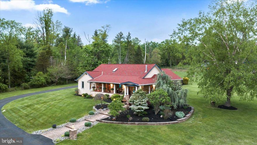 Welcome to Casa d’Oro—a one-of-a-kind, exquisitely maintained, Mediterranean-inspired villa set on two serene acres in desirable Wrightstown Twp. Bordering a picturesque horse farm and tucked at the end of a long driveway that wraps around to the rear entrance garage, this custom-built ranch offers a rare blend of timeless character, refined finishes, and peaceful seclusion. Designed for both everyday living and elegant entertaining, the home showcases a stunning open floor plan highlighted by soaring vaulted ceilings, light-filled interiors, and rich Brazilian teak hardwood floors. The gourmet kitchen—once featured in Nouveau Magazine—is a true centerpiece, appointed with custom cabinetry, display shelving, and high-end gas appliances, seamlessly flowing into the expansive great room with exposed wood beams, gas fireplace and a striking spiral staircase. A spacious loft with skylights overlooks the main living area, offering a flexible space for a home office, studio, or guest retreat. The primary suite is a private sanctuary, complete with an oversized walk-in closet, a beautifully updated bath, and French doors that open to a secluded covered porch—perfect for quiet mornings or evening relaxation. Outdoor living is equally exceptional. Thoughtfully designed hardscaping, capped garden walls, landscape lighting, and lush ornamental plantings create a resort-like setting. While accessable to many of the inside rooms, the wraparound covered porch with ceiling fans invites year-round enjoyment of the surrounding natural beauty. Additional features include limestone flooring in the foyer, kitchen and dining areas, a two-car garage with attic access via permanent stairs, and countless custom details throughout. Enjoy the highly regarded Council Rock School District or choose from a selection of prestigious private schools nearby. A true one-of-a-kind offering, Casa d’Oro embodies warmth, craftsmanship, and understated luxury—an exceptional place to call home!