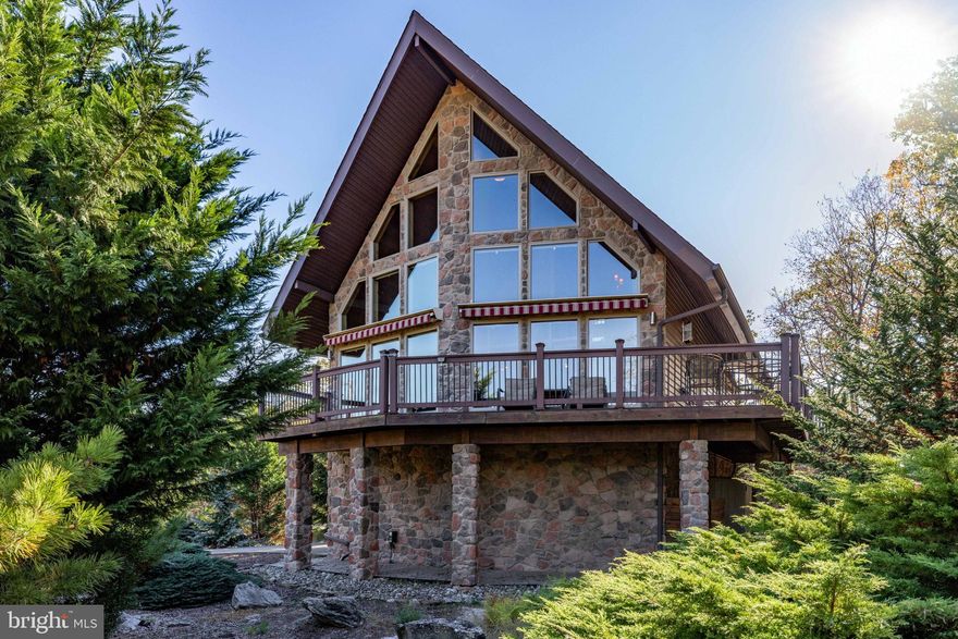 Escape to Eagle Rock Resort to a world of rustic luxury in this breathtaking chalet, where every detail invites relaxation and connection with nature. Enjoy your .91 acres of land. The moment you step inside, you'll be captivated by the soaring, vaulted ceilings and a stunning wall of windows that flood the space with natural light. The warm pine tongue and groove walls flows througout the home,

creating a cohesive and inviting atmosphere. The open concept living area, and majestic stone fireplace, is the perfect backdrop for cozy gatherings and memorable moments.
This home is designed for comfort and privacy. A sculptural spiral staircase with sleek metal railings and warm wood treads elegantly connects the main floor to the upper loft, where a primary bedroom with a full ensuite bathroom awaits. Two additional bedrooms and another full bathroom on the main level provide ample space for the family or guests. The gourmet kitchen, complete with modern appliances and a large breakfast bar, is an entertainer's dream. Imagine sipping your morning coffee on the expansive wrap-around deck, where three electric awnings provide shade at the touch of a button.
For those who work from home or desire a quiet retreat, the finished lower level provides a versatile and private space. Bathed in the same beautiful wood as the main level, it's the perfect dedicated home office but could also serve as a cozy den or recreation room. Venture outside to find your personal sanctuary. A private, stone-walled patio awaits below, complete with an area for a barbecue grill and plenty of room for al fresco dining. Just steps away, a secluded hot tub is nestled among natural rock formations, offering the ultimate spot to unwind under the stars. This home has a whole-home generator and central air conditioning ensure comfort no matter the season. This chalet isn't just a place to live; it's a lifestyle, offering a peaceful sanctuary with all the modern comforts.
Beyond the home, a world of amenities awaits. This property is nestled within a community that offers a truly exceptional lifestyle. 24/7 security where all guests must check-in. Enjoy year-round recreation with two golf courses - an 18-hole Arnold Palmer designed course and a 9-hole Executive course. Take a dip in one of the three outdoor pools or head to the Aquatic Center, which features three additional pools and a hot tub. The community lake is perfect for fun with a sandy beach, barbecue, picnic areas, and paddle boats. For snow lovers, winter brings the thrill of snow tubing and skiing. The Equestrian Center offers horseback riding and boarding, and you can stay active on the tennis, pickleball, volleyball, bocce, and cornhole courts. After a day of activity, relax at the on-site clubhouse restaurant and bar or unwind at the full-service spa with a gym and sauna. A vibrant calendar of social events is held throughout the year, ensuring there's always something to do.
All measurments are estimates.