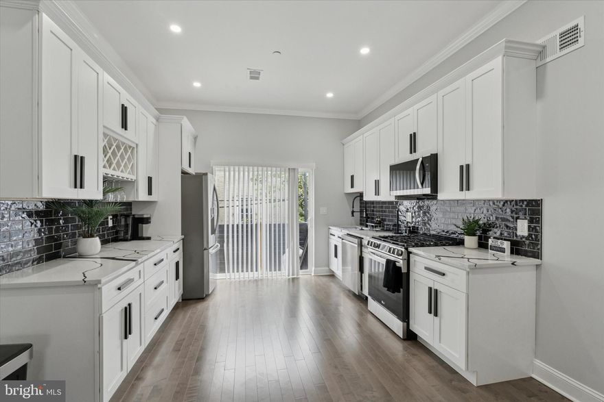 SELLER NOW OFFERING $5,000 towards your closing costs at closing. Get everything you expect in a newly built home–stylish contemporary kitchen and baths, finished basement, and a full-floor primary suite–along with a beyond-impressive skyline view in a great Point Breeze location. This is the last house on the block that ends at Wharton Square Park, putting the park entrance in view from your front steps. The open-plan first floor has super high ceilings with crown molding, recessed lighting and hardwood floors through the living, dining and showroom kitchen. Here 42-inch white Shaker-style cabinets have contrasting black hardware and a glossy black subway tile backsplash and quartz countertops with thick black veining. The stainless steel LG appliance package includes a slide-in range with convection oven and French door fridge. This level gets great natural light from an oversized front casement window and sliders to the rear, which offers a nice-size patio with privacy fence. No fighting over who gets which room–the second floor has two bedrooms of equal generous size with large closets, and there’s a large hall bath with marble vanity, Smart mirror, large-format veined porcelain tile floor and full-wall surround in the step-in shower with penny tile floor and frameless glass doors. The primary suite occupies the third floor, offering a good-sized bedroom, large walkthrough closet and a resort-worthy bathroom with a marble double vanity with Smart mirror, dramatic soaking tub and large-format charcoal porcelain tile floor and full-wall surround in the large shower with frameless glass doors. There’s a wet bar at the landing on the way out to the roof deck with absolutely jaw-dropping panoramic skyline views to the north and treetops from the park to the west. There’s another 500-plus square feet of living space in the basement, which has a handsome powder room, laundry closet with LG Thinq frontloaders, and a large space at the back for whatever you need–home office, playroom or media room. In addition to being super close to the park, you're just three blocks to a stretch of Washington Ave that’s seeing an explosion of new retail and dining, both up-and-running and coming soon.