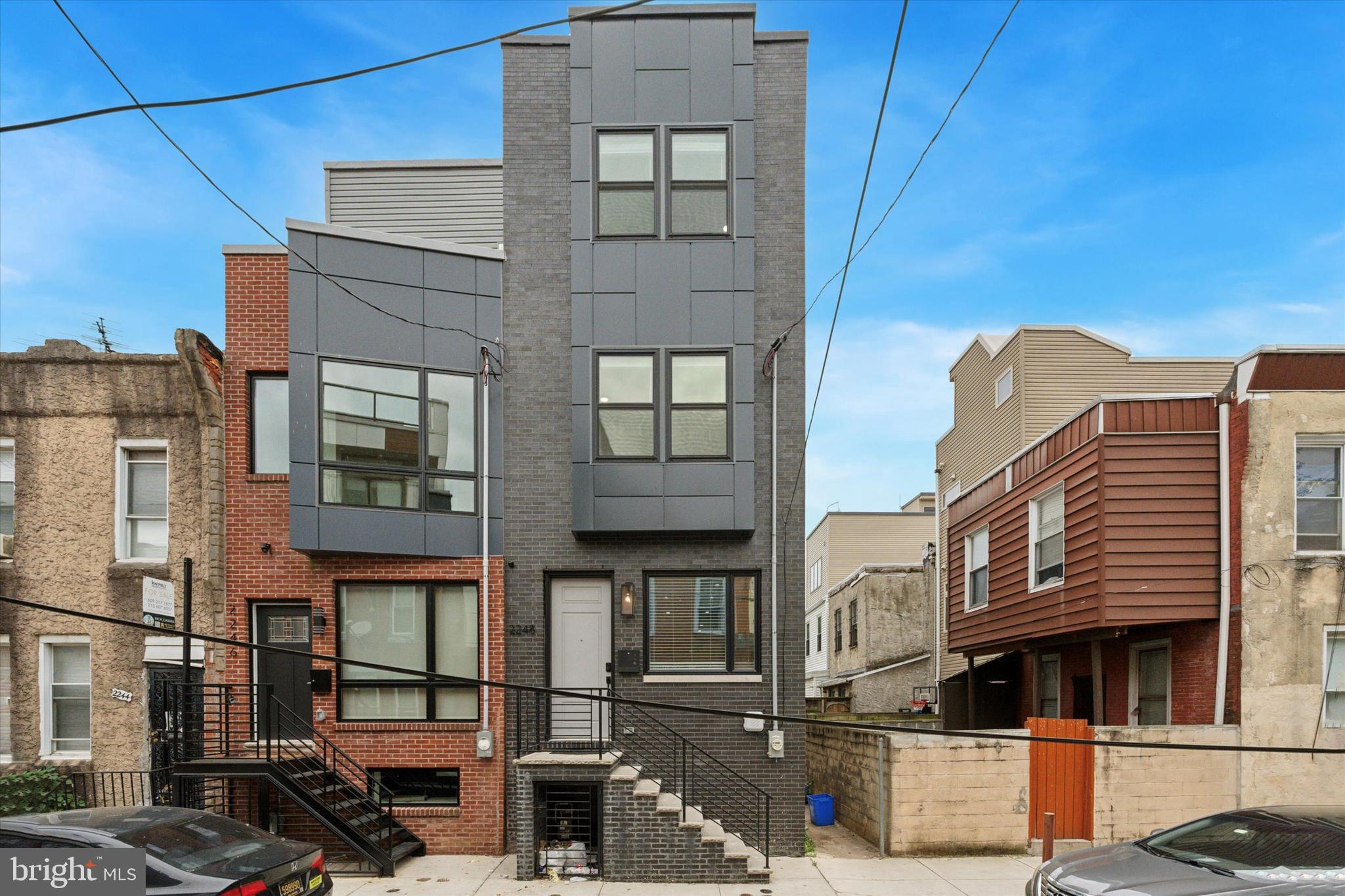Get everything you expect in a newly built home–stylish contemporary kitchen and baths, finished basement, and a full-floor primary suite–along with a beyond-impressive skyline view in a great Point Breeze location. This is the last house on the block that ends at Wharton Square Park, putting the park entrance in view from your front steps. The open-plan first floor has super high ceilings with crown molding, recessed lighting and hardwood floors through the living, dining and showroom kitchen. Here 42-inch white Shaker-style cabinets have contrasting black hardware and a glossy black subway tile backsplash and quartz countertops with thick black veining. The stainless steel LG appliance package includes a slide-in range with convection oven and French door fridge. This level gets great natural light from an oversized front casement window and sliders to the rear, which offers a nice-size patio with privacy fence. No fighting over who gets which room–the second floor has two bedrooms of equal generous size with large closets, and there’s a large hall bath with marble vanity, Smart mirror, large-format veined porcelain tile floor and full-wall surround in the step-in shower with penny tile floor and frameless glass doors. The primary suite occupies the third floor, offering a good-sized bedroom, large walkthrough closet and a resort-worthy bathroom with a marble double vanity with Smart mirror, dramatic soaking tub and large-format charcoal porcelain tile floor and full-wall surround in the large shower with frameless glass doors. There’s a wet bar at the landing on the way out to the roof deck with absolutely jaw-dropping panoramic skyline views to the north and treetops from the park to the west. There’s another 500-plus square feet of living space in the basement, which has a handsome powder room, laundry closet with LG Thinq frontloaders, and a large space at the back for whatever you need–home office, playroom or media room. In addition to being super close to the park, you're just three blocks to a stretch of Washington Ave that’s seeing an explosion of new retail and dining, both up-and-running and coming soon.
