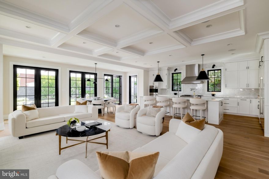 Set against the iconic backdrop of the National Cathedral in the heart of verdant Cathedral Heights, 3117 38th Street NW is a masterfully crafted modern farmhouse designed by GTM Architects in collaboration with MMg Development and built by Murillo/Malnati Homes. This distinguished team partnered with acclaimed landscape designer Lila Fendrick to deliver a residence that marries high design with luxurious livability, showcasing top-tier craftsmanship, seamless indoor-outdoor flow, and enduring style.

Completed in 2019, the home spans nearly 8,000 finished square feet across four thoughtfully designed levels. A white brick façade, black-trimmed windows, flagstone walkways, and manicured landscaping create timeless curb appeal. The front portico opens to a gracious foyer with sightlines that extend to the rear terrace, setting a tone of openness and elegance. Crown moldings, gleaming hardwood floors, and abundant natural light provide a sophisticated yet welcoming atmosphere.

The formal living room, with a gas fireplace and custom built-ins, overlooks the front garden. A tray ceiling and wainscoting in the adjacent dining room elevate formal gatherings. A marble-clad butler’s pantry with a beverage fridge connects seamlessly to the chef’s kitchen, which features custom stacked cabinetry, Wolf and Sub-Zero appliances, a full-height marble herringbone backsplash, and an expansive island with bar seating.

The open-concept kitchen and adjoining family room serve as the heart of the home. Coffered ceilings, a marble fireplace, and dual sets of French doors open to a flagstone terrace beneath a full-width pergola, perfect for indoor-outdoor entertaining and framed by views of the Cathedral.
Additional main-level features include a custom mudroom with built-in cubbies and side entry, access to a detached two-car garage with EV hookup, and a large walk-in pantry. A powder room and elevator complete this level.

Upstairs, the primary suite occupies its own wing and includes a private rear deck with cathedral views. The spa-inspired primary bath features radiant heated marble floors, a freestanding soaking tub, a glass-enclosed shower, a wall-spanning double vanity, and a private water closet. A custom dressing room with golden backlit shelving and abundant storage completes the suite. Three additional bedrooms, one currently used as a home office, share two full bathrooms along with a large, fully equipped laundry room.

The third level offers flexible living with two additional bedrooms, one styled as a game room with alcove seating, and a full bath. This space is ideal for guests, teens, or creative pursuits.

The finished lower level includes high ceilings, a recreation room with integrated Sonos sound, a wet bar with a Sub-Zero beverage fridge, a custom wine room, a fitness studio, a powder room, and a second laundry area. A private guest or au pair suite features a kitchenette, bedroom, and full bath.

Smart home systems include Legrand lighting, Honeywell Pro Series thermostats, integrated security with cameras and motion sensors, and multiple wall-mounted iPads for controlling lighting, sound, and surveillance.

Outdoors, a flat, professionally landscaped lawn is pool-ready and features a built-in grilling station, an extensive stone terrace, ambient lighting, irrigation, and French drainage systems for year-round enjoyment.
Steps from Massachusetts and Wisconsin Avenues, this premier location offers proximity to top-rated schools, lush parkland, and downtown DC. Elegant yet approachable, richly appointed yet supremely functional, 3117 38th Street NW is a rare offering that defines modern luxury living in Washington.