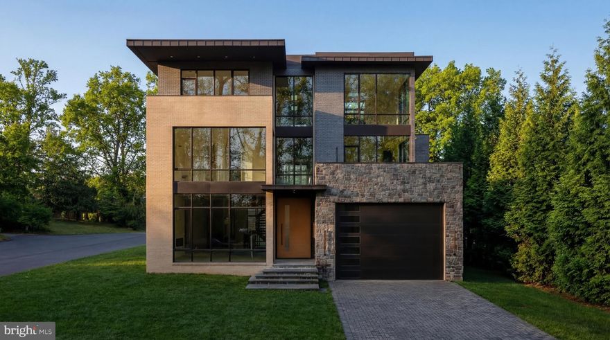 Tucked away on a quiet, wooded street in coveted Chevy Chase DC, 2717 Tennyson Street NW is a newly constructed contemporary residence distinguished by an exceptional connection to its natural surroundings. Immediately bordering the verdant sanctuary of Rock Creek Park, the home captures rare, uninterrupted views of lush greenery, an experience seldom found within the city. Crisp angles, a blend of contrasting materials, and expansive glass area by Kolbe & Kolbe creates a dramatic curb appeal. A custom 11-foot aluminum and wood entry door introduces the grand interior, opening into a gallery-like foyer with through sightlines to the rear terrace and framed by a sweeping staircase. Spanning nearly 10,000 square feet, formal and informal rooms are thoughtfully arranged for both grand-scale entertaining and comfortable daily living. European white oak flooring, installed using a special glue-down method, recessed baseboards, solid-core doors with 1½-inch jambs, and bespoke maple wall paneling create a refined, gallery-like interior and serve as a testament to the attention to detail found in every square inch of the property. Throughout, floor-to-ceiling windows and oversized glass doors frame the verdant canopy of Rock Creek Park, flooding the interiors with natural light and creating a constant dialogue with the outdoors. In the principal living spaces, broad panes of glass transform the surrounding trees into a living backdrop, changing with the seasons. Four Napoleon fireplaces infuse warmth into these spaces. The centerpiece of the residence’s more casual spaces is the striking chef’s kitchen. Equipped with a comprehensive suite of Thermador Professional Series appliances, neatly integrated into fully custom cabinetry and natural stone surfaces imported from Brazil, the space is a poster child for streamlined luxury. Adjacent living and dining spaces flow seamlessly outward to terraces and outdoor entertaining areas, extending the home’s connection to its serene setting. Upstairs, the primary suite serves as a private retreat, complete with a private terrace offering sweeping wooded views, a generous dressing room, and a lavish primary bath clad in Porcelanosa marble, featuring a steam shower room and radiant heated floors. Seven additional bedrooms and ten bathrooms throughout are each outfitted with exotic stonework and Delta fixtures, offering ample accommodation. The home is a hub for thoughtfully integrated wellness and recreation amenities. A dedicated fitness center with professional rubber flooring is supported by a sauna and promotes a wellness-oriented lifestyle, while a climate-controlled wine cellar with 200-bottle capacity adds a refined entertaining element. Mechanical systems supporting the property promote energy efficiency, including four-zone Carrier high performance HVAC controlled by Nest smart thermostats, a garden roof, EV charging station, and permeable driveway and patios. The outdoor space is another showstopper. The highlight of which is an expansive 40-by-20-foot lap pool with integrated spa anchoring the rear grounds to create a private resort-like setting. Above, a rooftop terrace prepared for an outdoor kitchen and grilling station offers elevated entertaining space and unbroken vistas. With its striking architecture, painstaking attention to detail and unparalleled location, 2717 Tennyson Street NW is a refreshingly sophisticated modern residence representing a forward-looking ideology into the notion of luxury urban living.